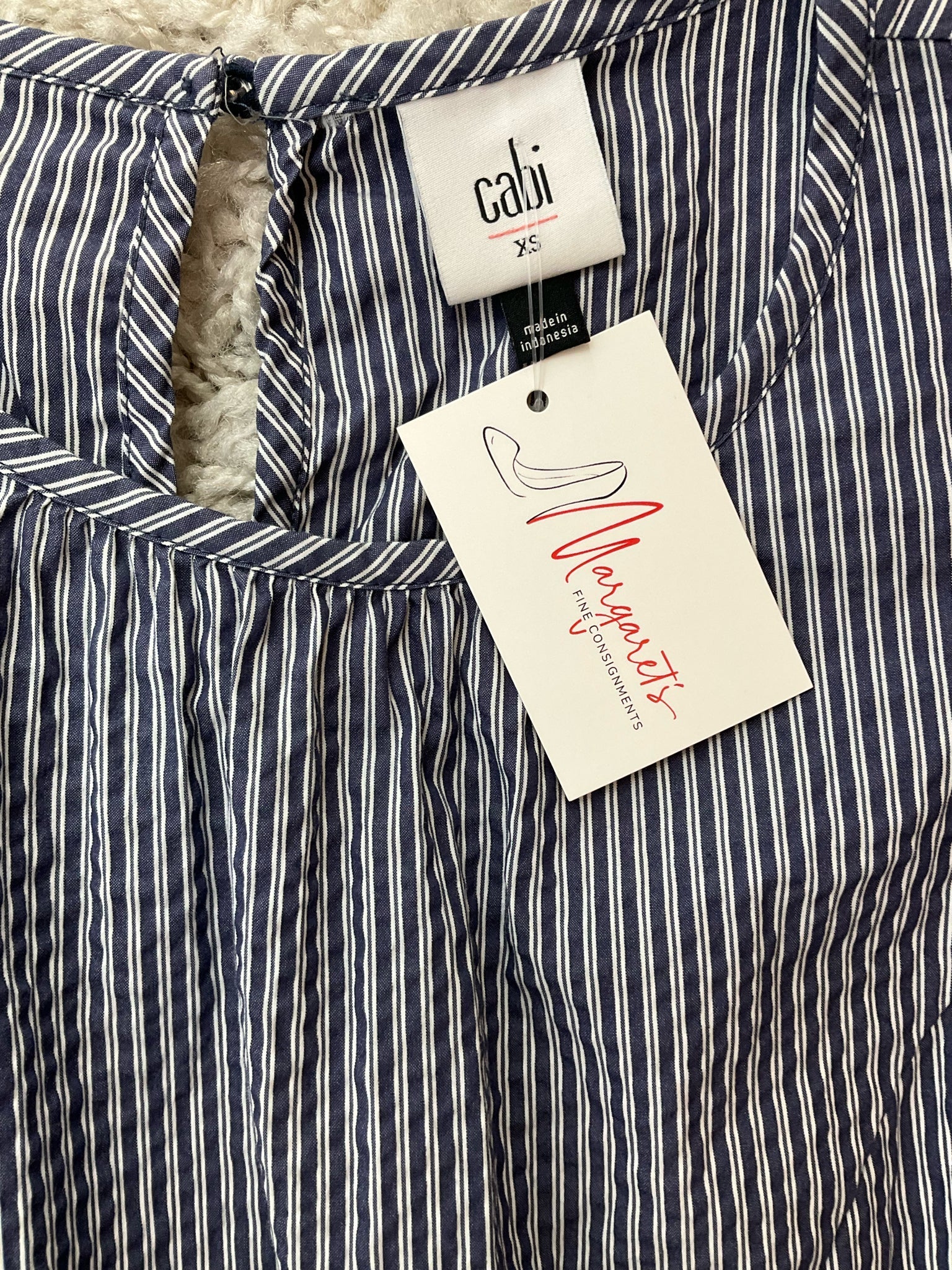 Close-up of Cabi Tapestry Top XS neckline and brand tag, featuring blue and white stripes and keyhole back with original label attached.