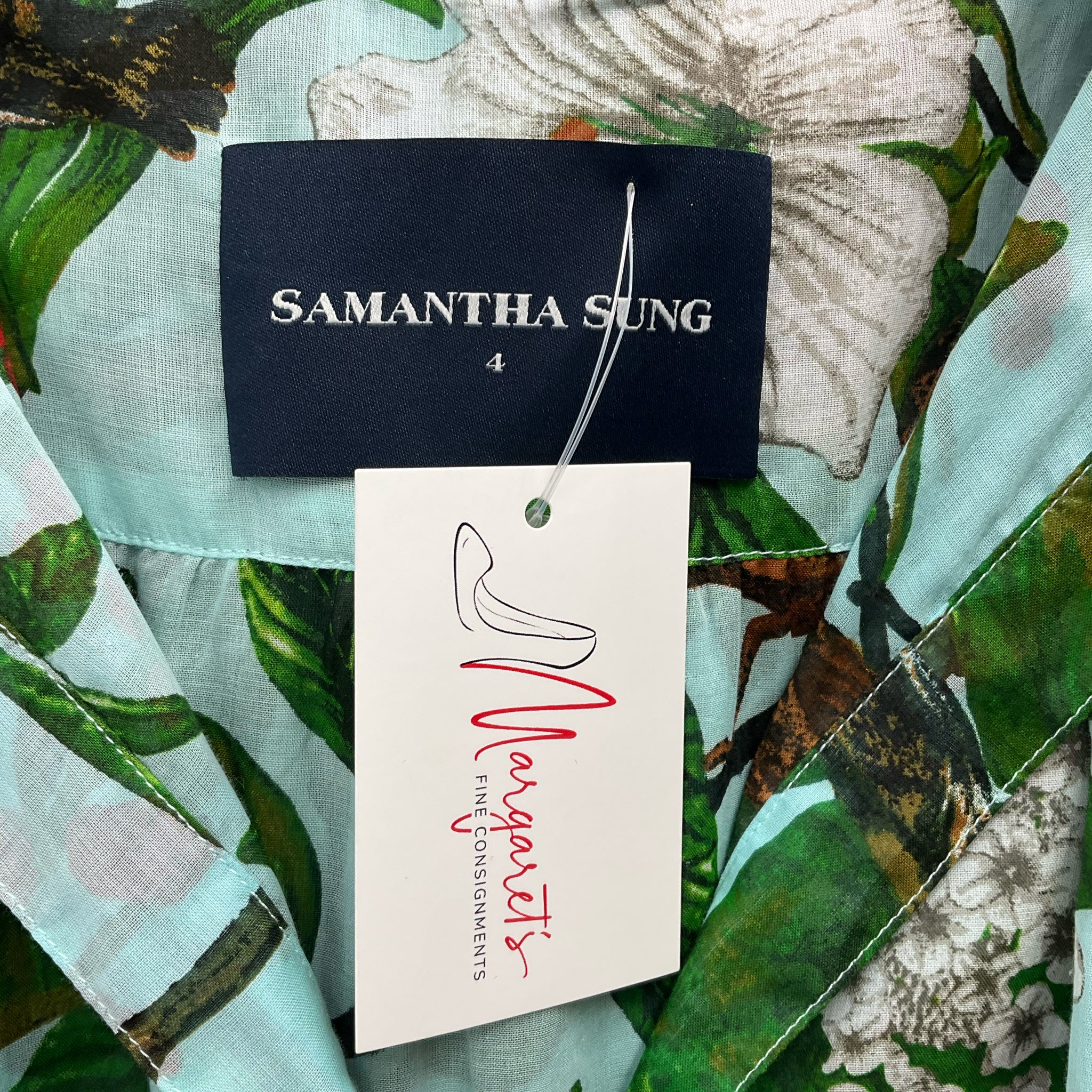Close-up of Samantha Sung brand label and Margaret’s Fine Consignments tag on Aqua/Green Floral Maxi Dress Size 4, gently used.
