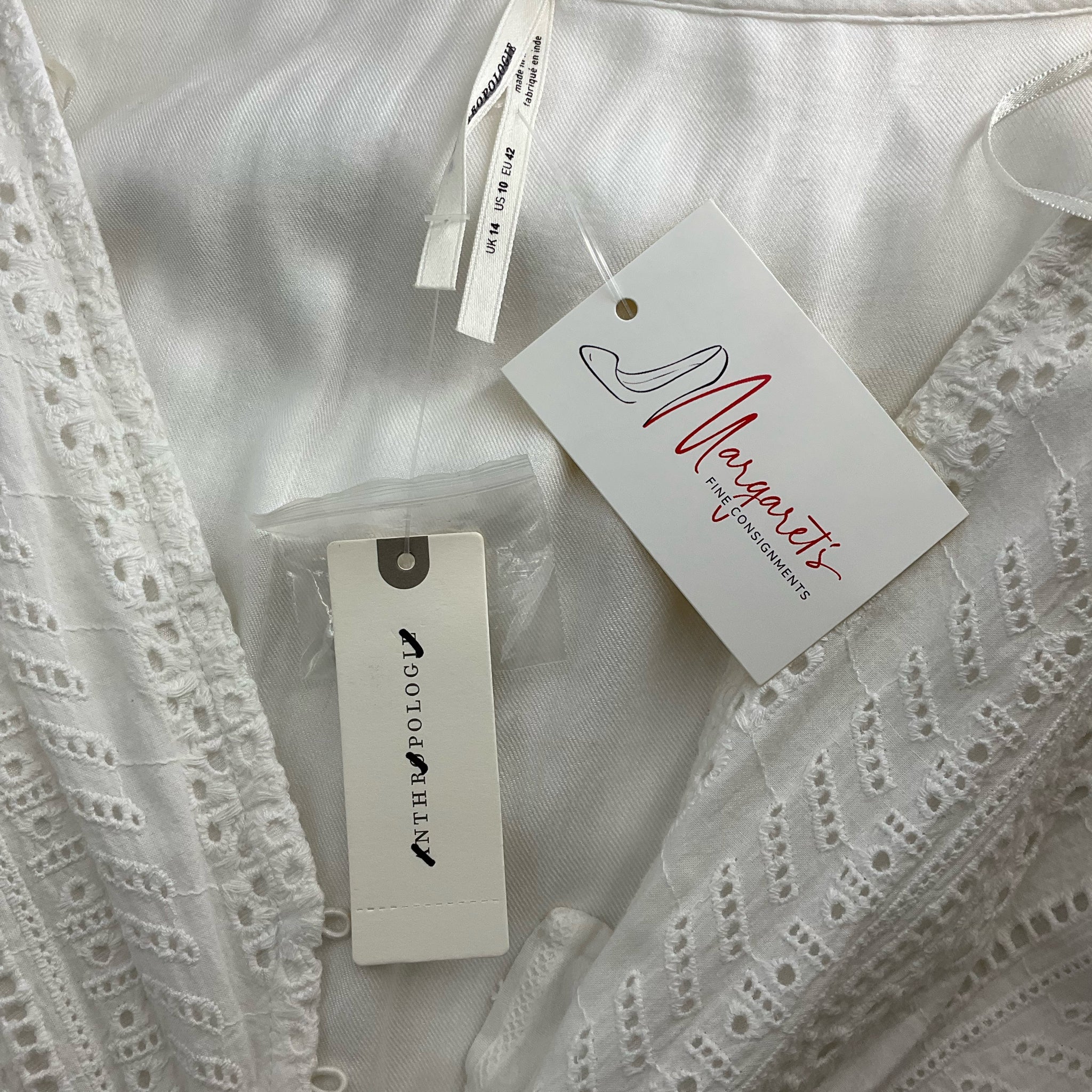 Close-up of Anthropologie White Solid Maxi Dress tags showing brand and Margaret’s Fine Consignments label, confirming new with tags status.