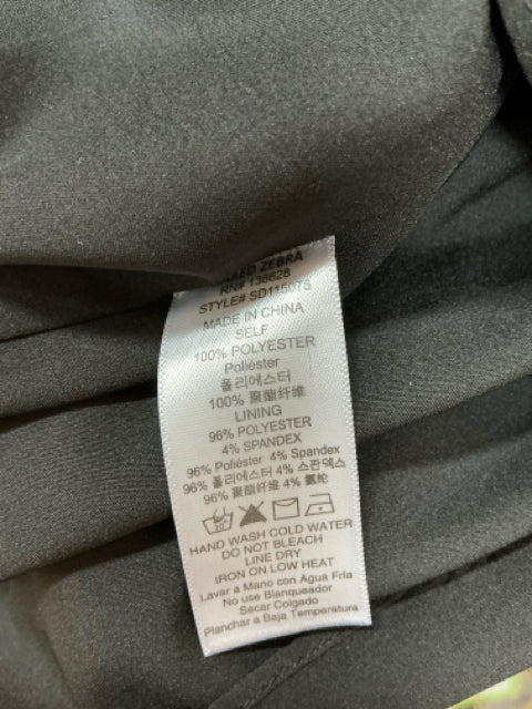 Close-up of fabric care label on Naked Zebra Black Pleated Dress, indicating 100% polyester material and washing instructions.