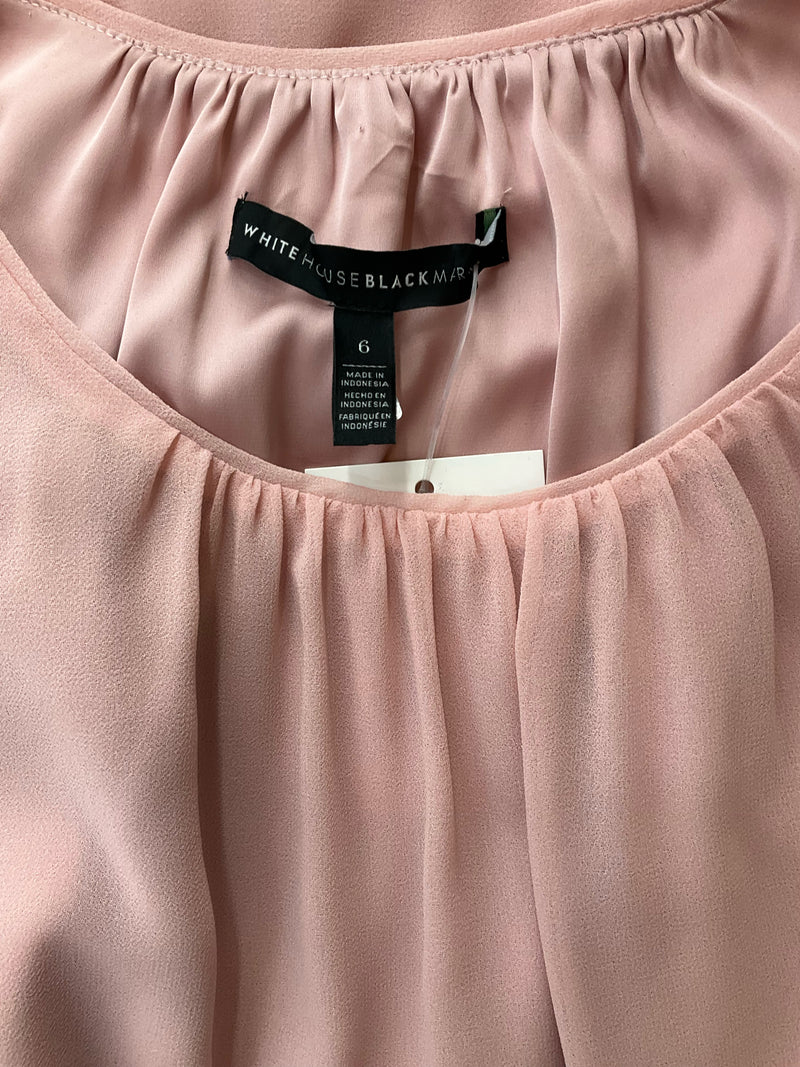 Close-up of White House Black Market label and size tag on pink sleeveless blouse, size 6. Features gathered neckline detail.