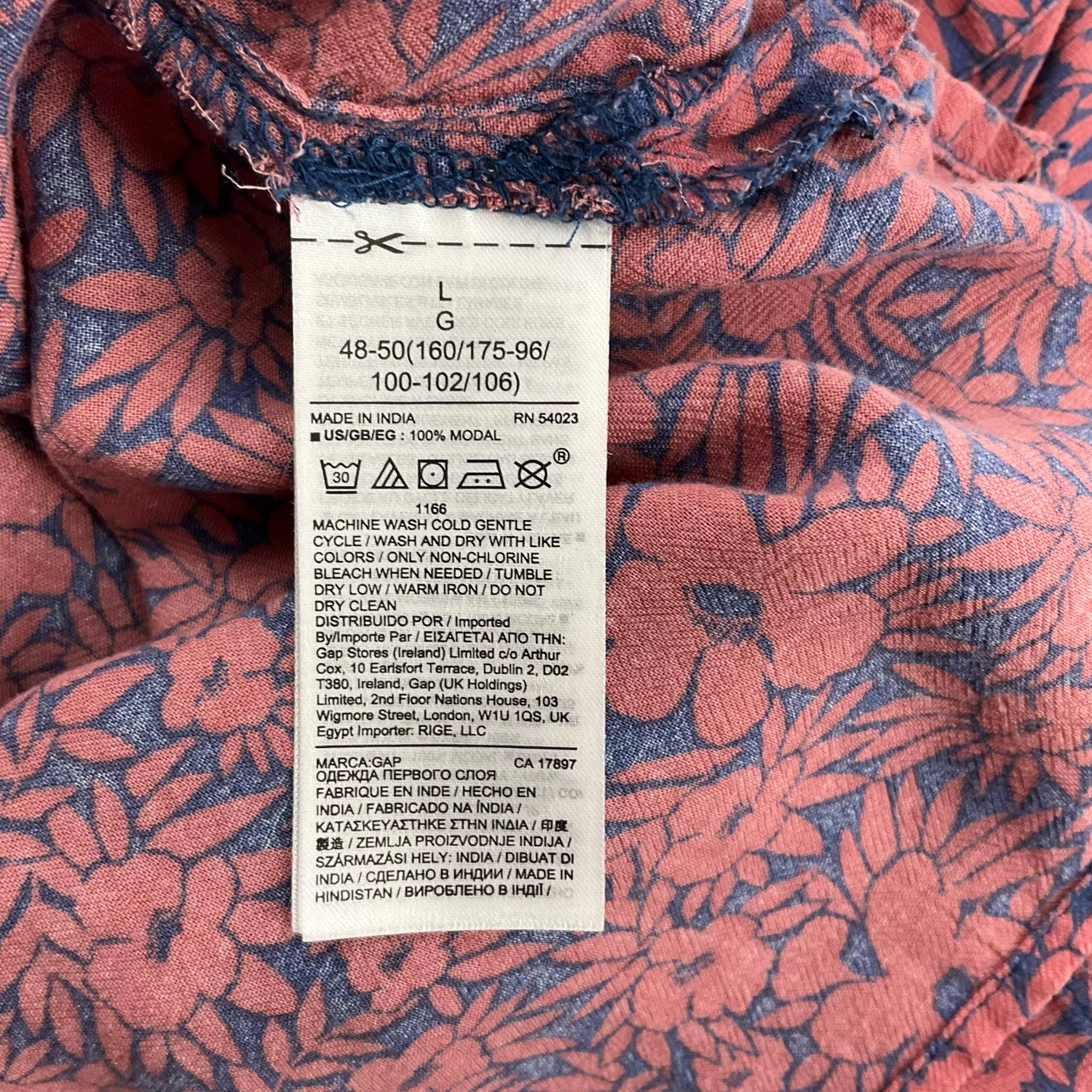 Fabric care and size tag of Gap V Neck Top - Floral Rust & Blue Top, size large, made of 100% modal for soft comfort.