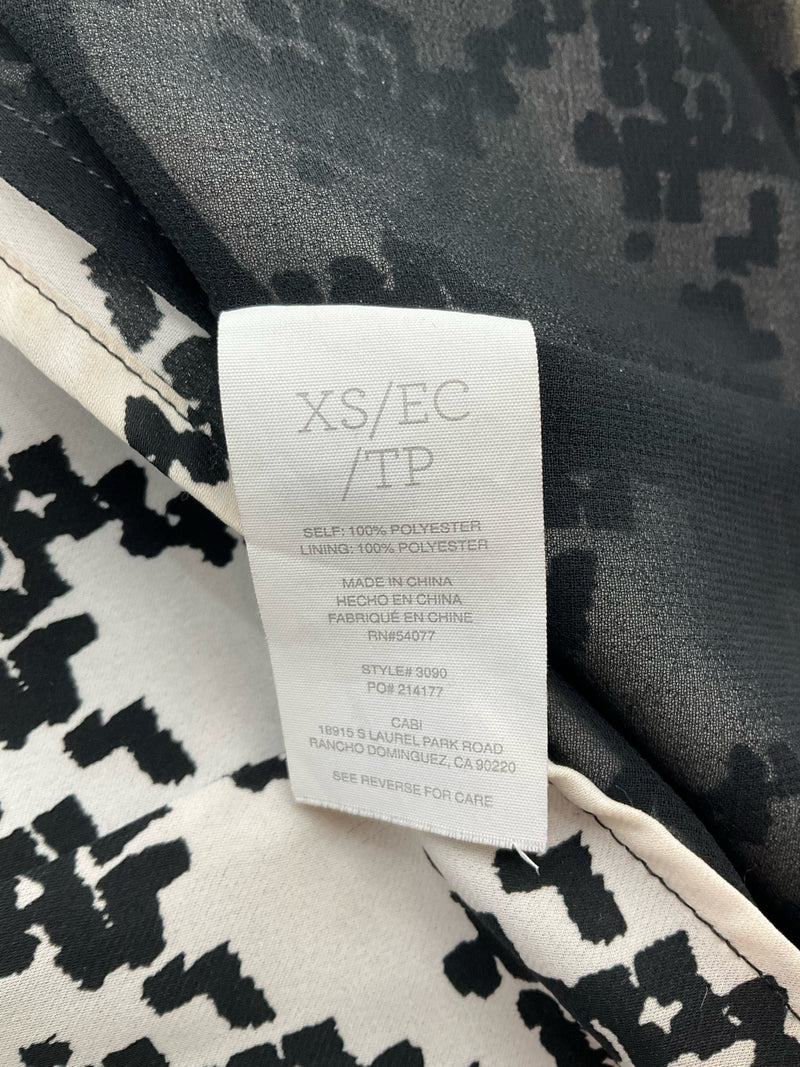 Interior care label of Cabi Pixel Houndstooth Tank Top Style 3090, size XS, showing 100% polyester fabric and RN 54077.