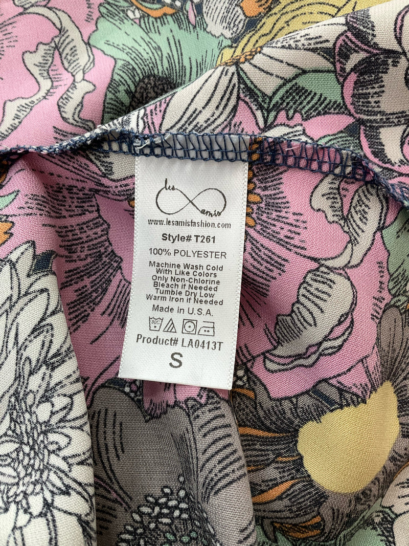 Fabric care label of Les Amis floral and polka dot blouse, style T261, 100% polyester, made in USA, size small, machine washable.