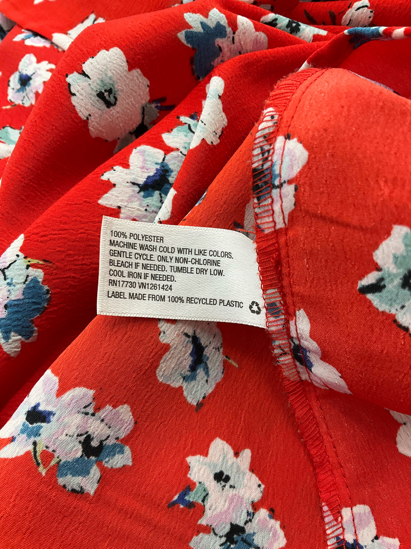 Fabric care label of Xhiliration Orange/Multi Floral Dress. Made of 100% polyester with recycled plastic label, machine washable.