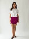 Model wearing Express Shorts Size 4 in fuchsia from Margaret’s Fine Consignments, styled with a white tee for a casual chic look.