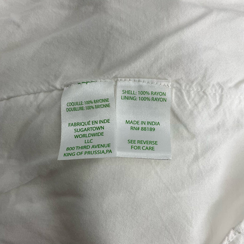 Fabric content tag of Lilly Pulitzer white top, size large, showing 100% rayon shell and lining. Made in India with sustainable materials.