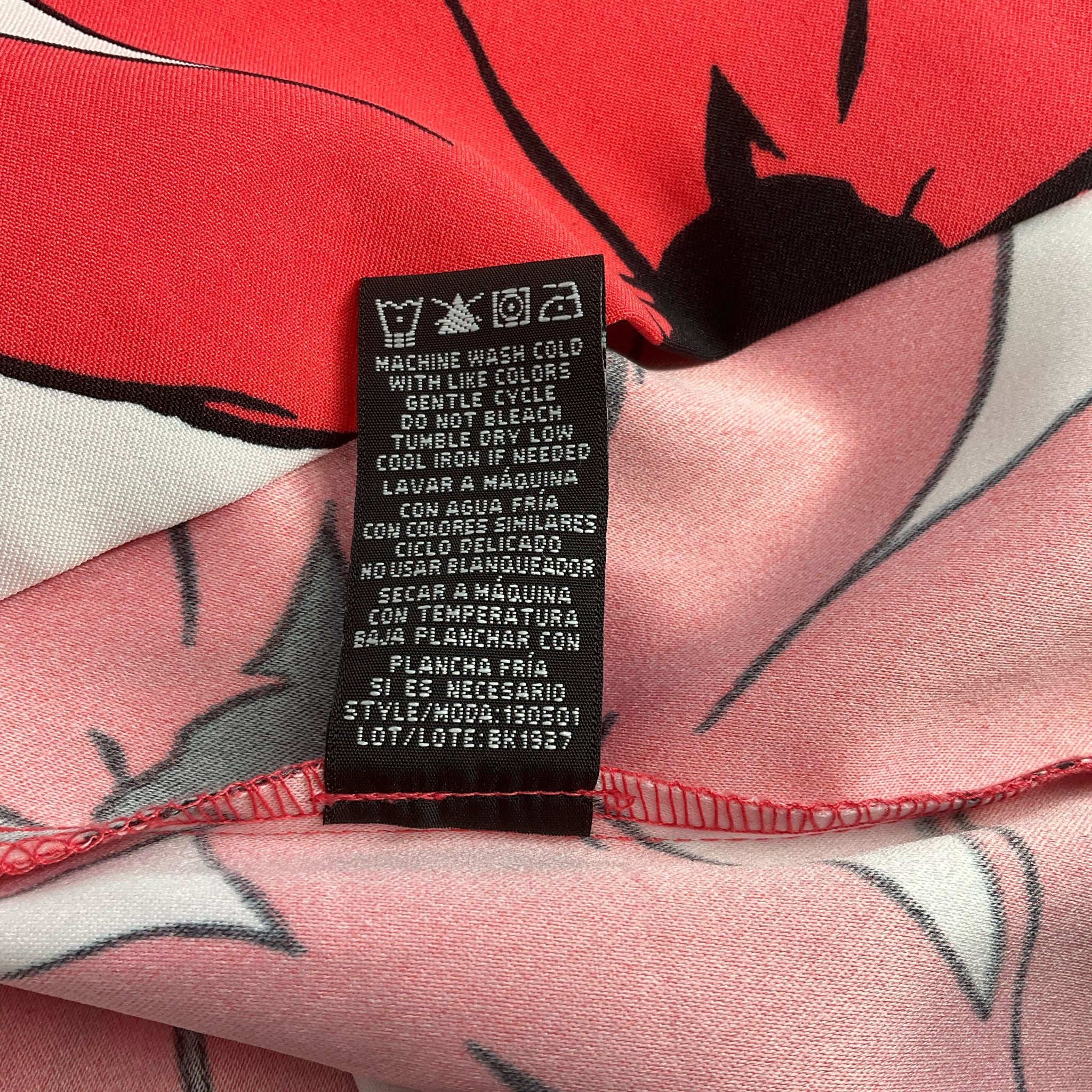 Care label of Ronni Nicole White/Coral Floral Dress - Size 8 with washing instructions, ensuring proper garment maintenance.