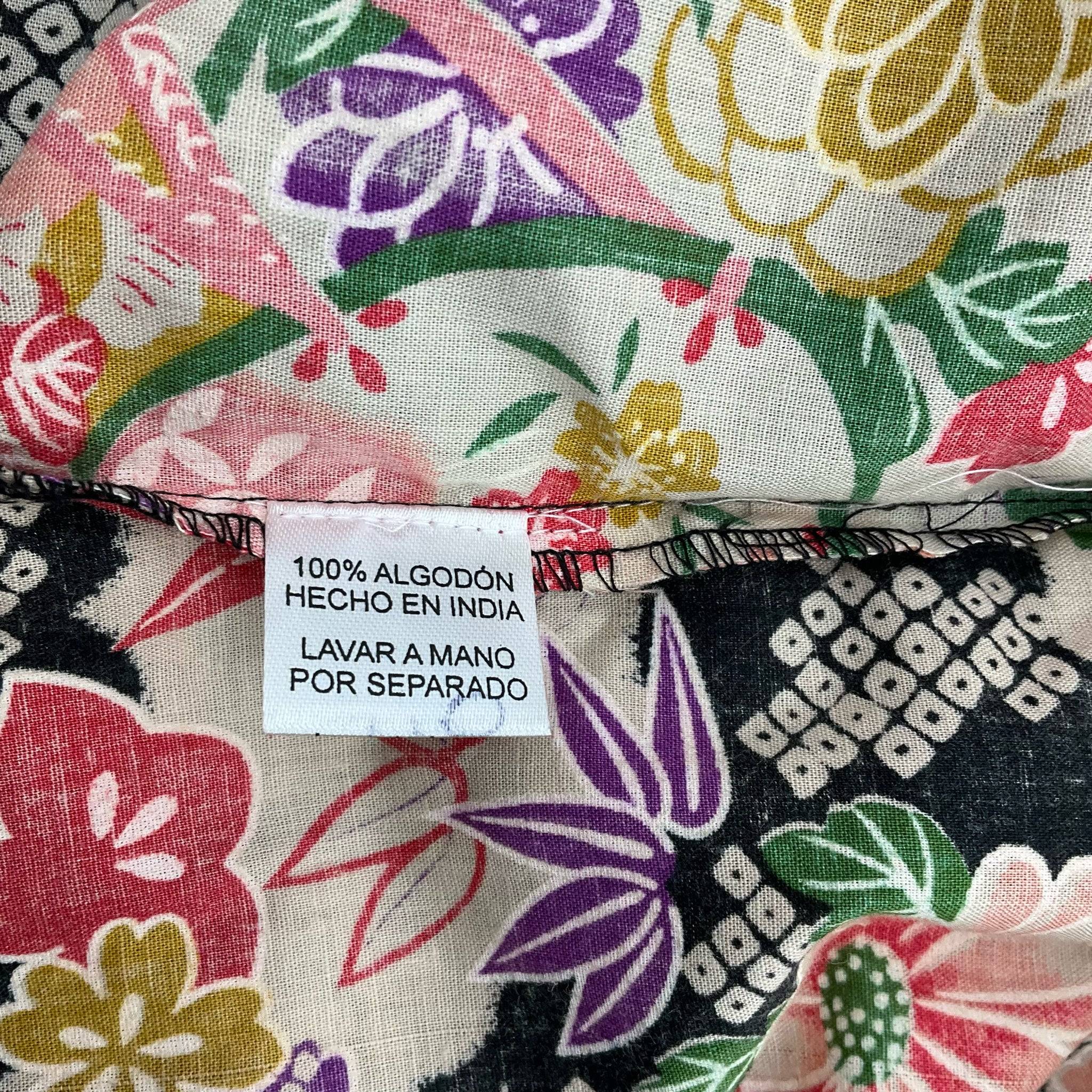 Fabric tag showing 100% cotton material and care instructions for 100% Pirata 1 Sleeved Mini Dress Size S/M at Margaret’s Fine Consignments.