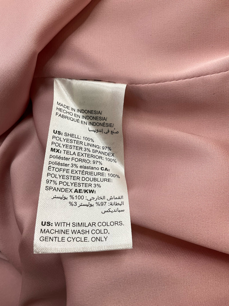 Fabric care label of WHBM pink blouse, showing 100% polyester shell and lining. Machine washable, made in Indonesia.