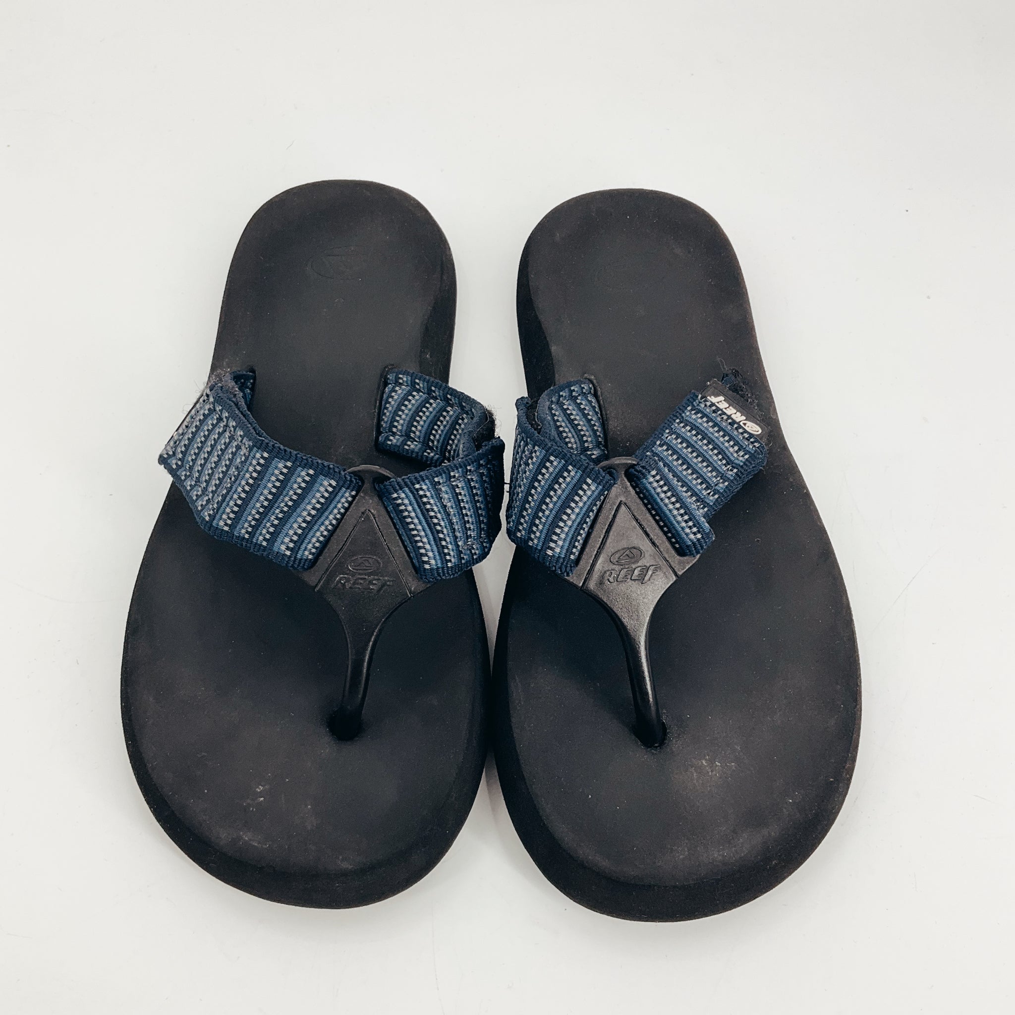 Pre-owned Reef size 8 thong sandals featuring navy and gray striped straps and cushioned black EVA soles, perfect for summer comfort.