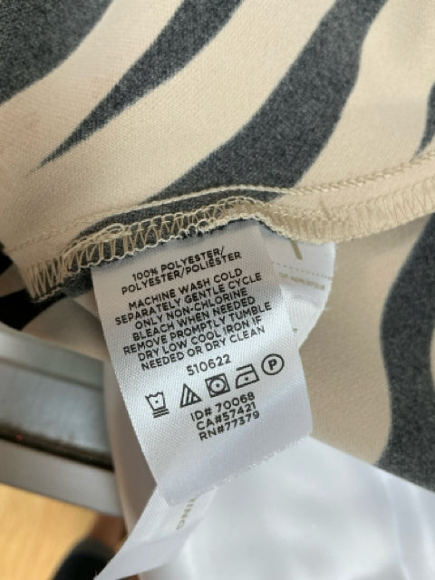 Close-up of care label on Ann Taylor zebra print dress, confirming 100% polyester fabric and machine washable instructions.