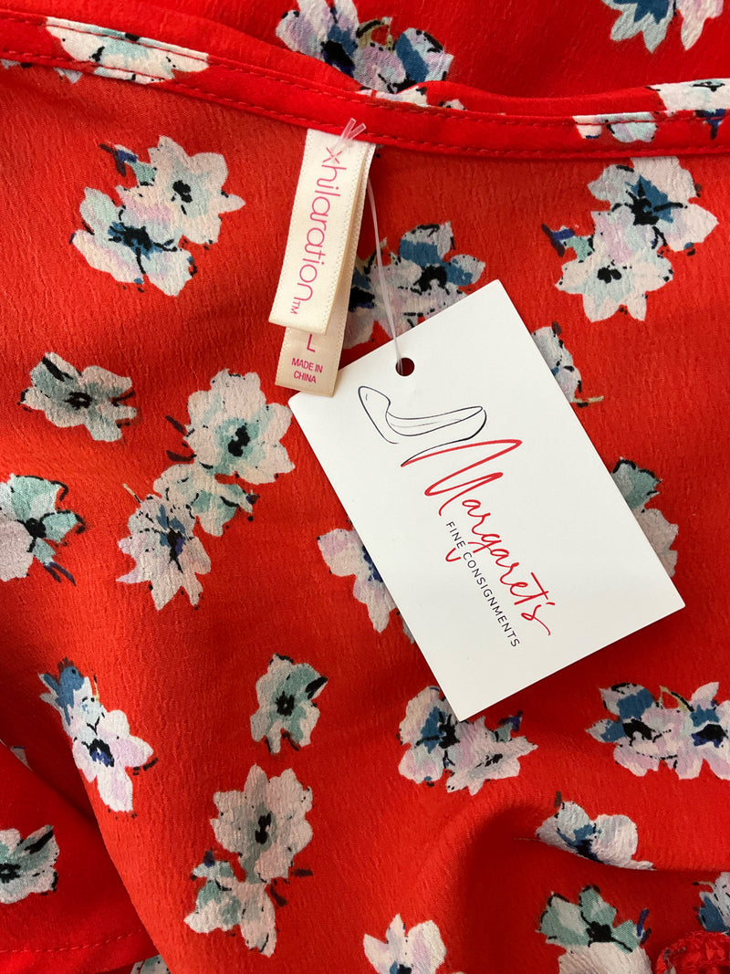Close-up of Xhiliration dress label and floral fabric. Shows size large tag and red background with white floral print.
