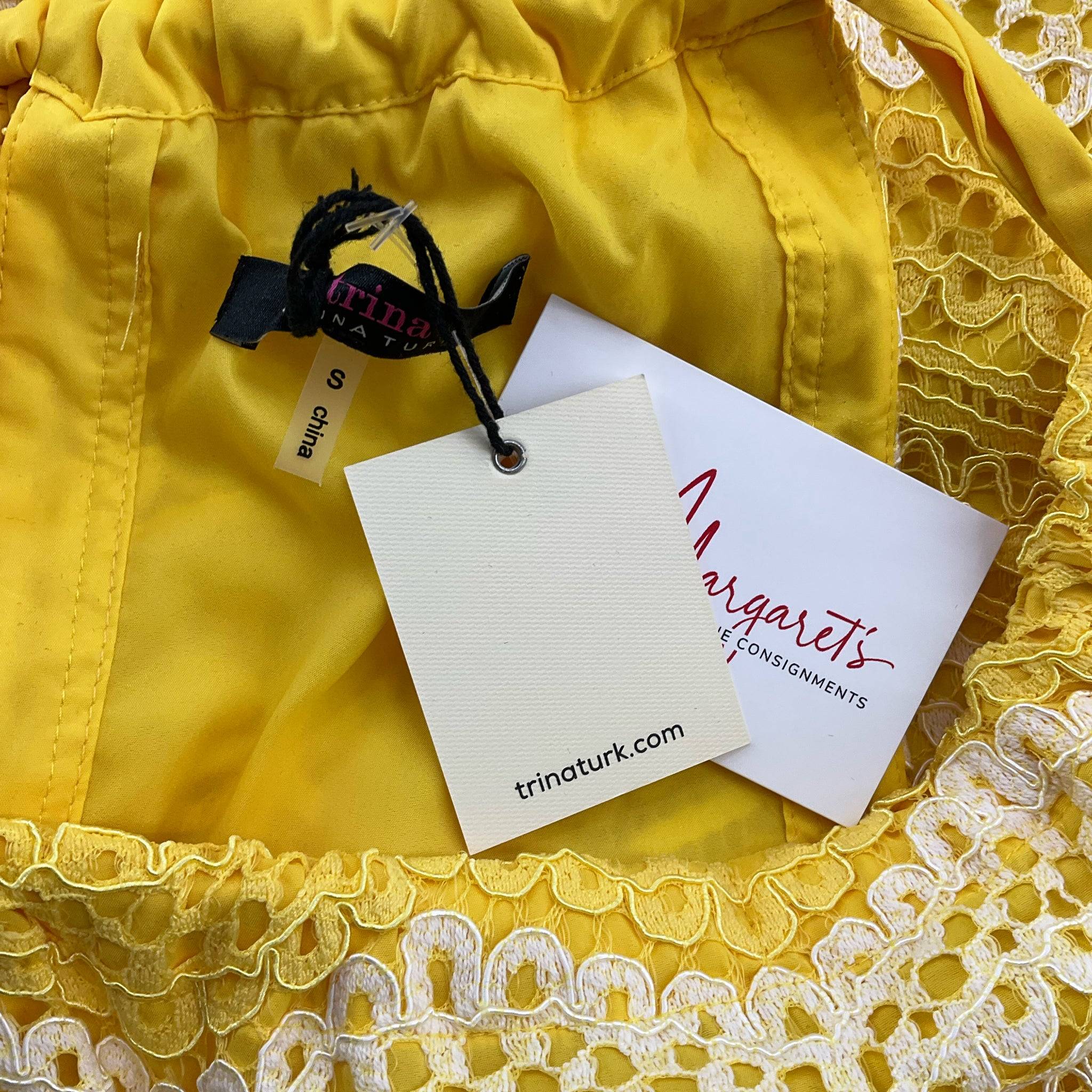 Close-up of Trina Turk Knee Length Dress Size Small tags showing brand and Margaret’s Fine Consignments label, confirming new condition.