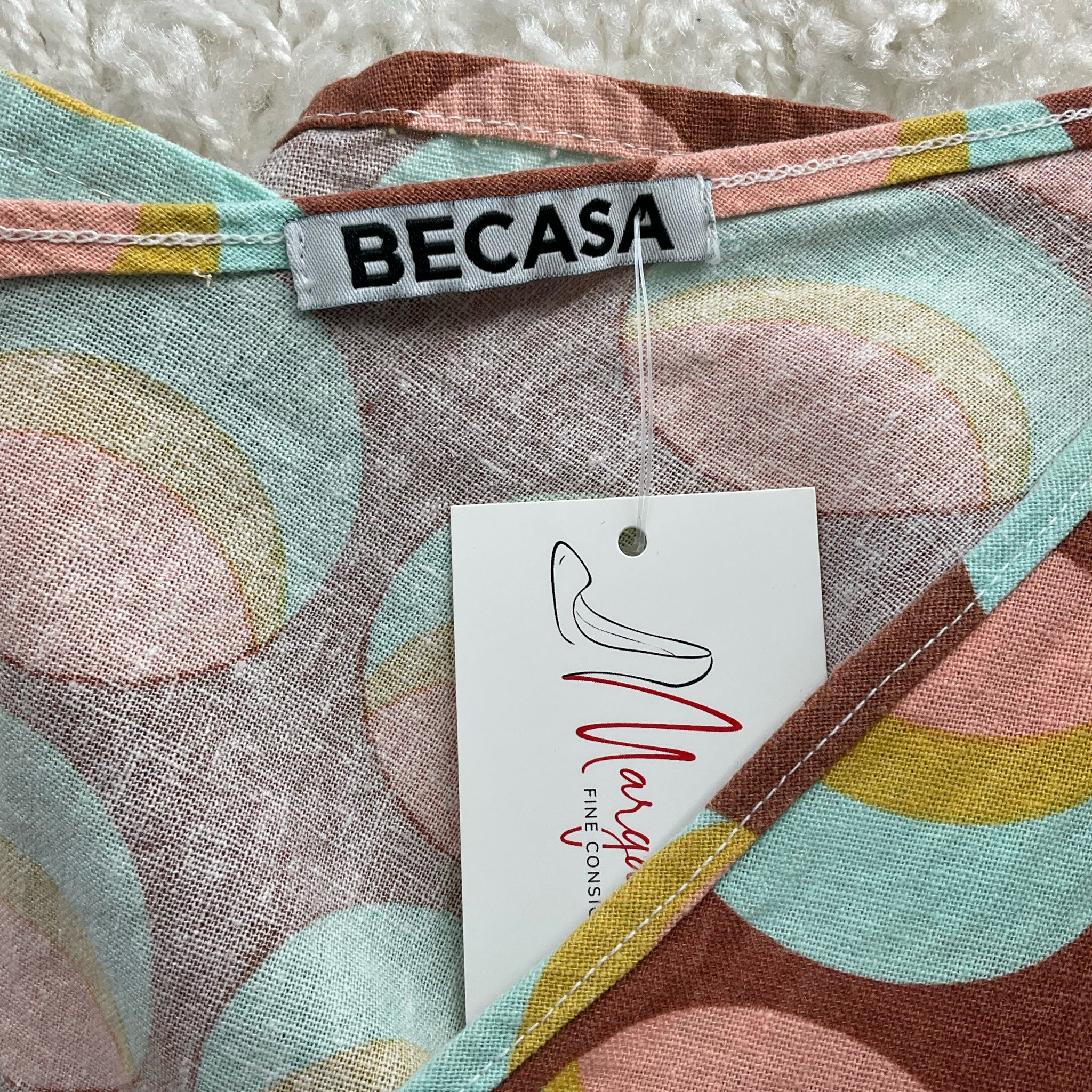 Close-up of Becasa brand label and Margaret’s Fine Consignments tag on Rust/Multi Circles Print Dress - Size XS. Unique pre-owned fashion piece.
