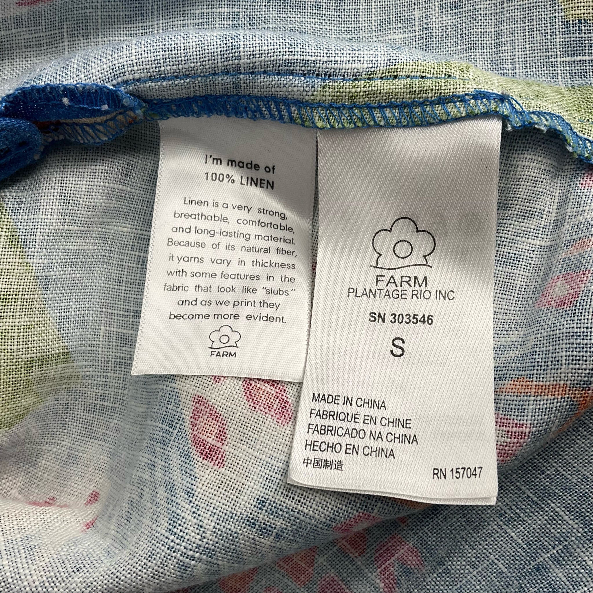 Fabric content tag on Farm Blue/Green Tropical Dress - Size Small, made of 100% linen for breathable, lightweight summer wear.