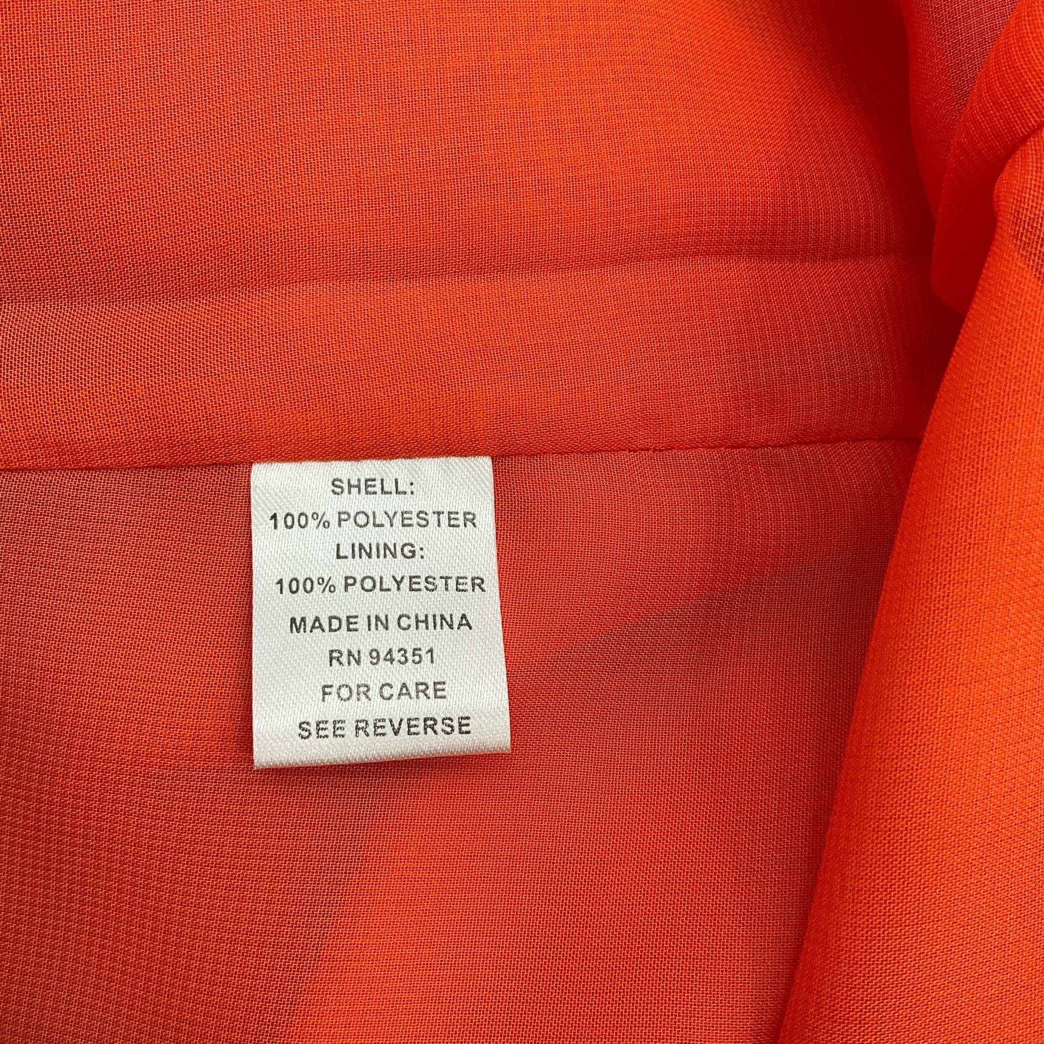 Fabric content tag on Jade orange ruffle dress, showing 100% polyester shell and lining, made in China, RN 94351.