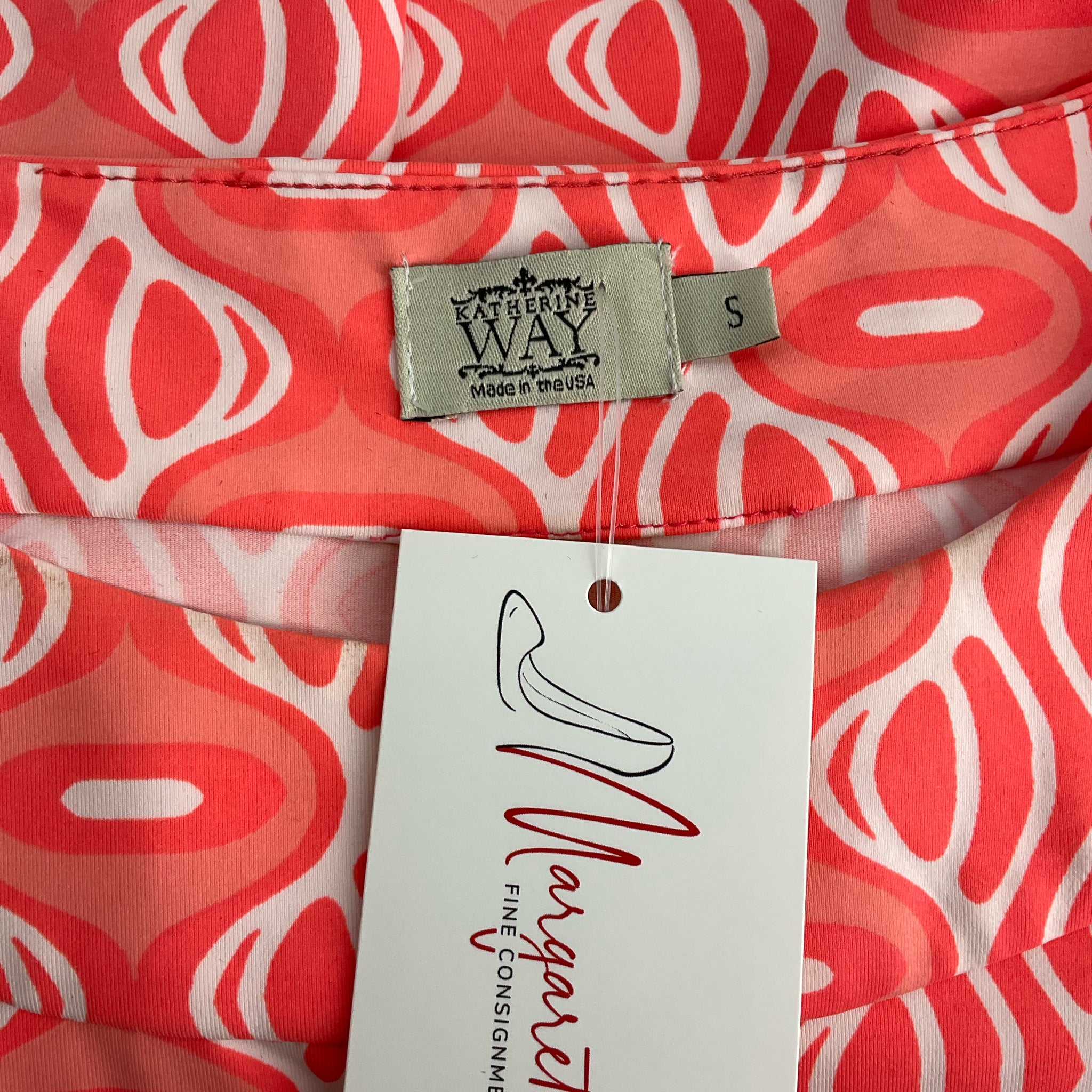 Close-up of Katherine Way brand label and Margaret's Fine Consignment tag on Coral/White Print Dress - Size Small, gently used.