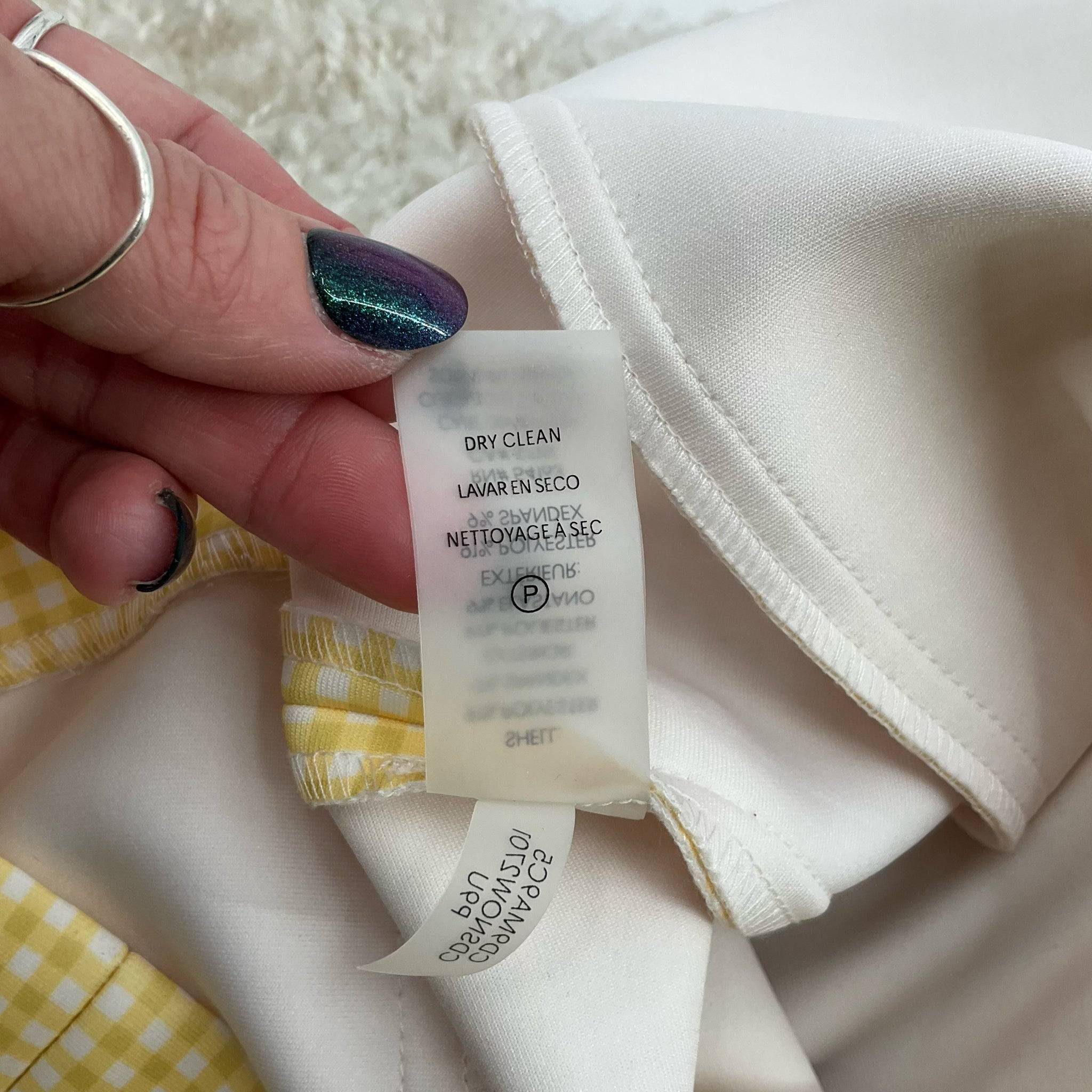 Close-up of dry clean care label inside Calvin Klein yellow and white checkered mini dress, size 12, sold at Margaret’s Fine Consignments.
