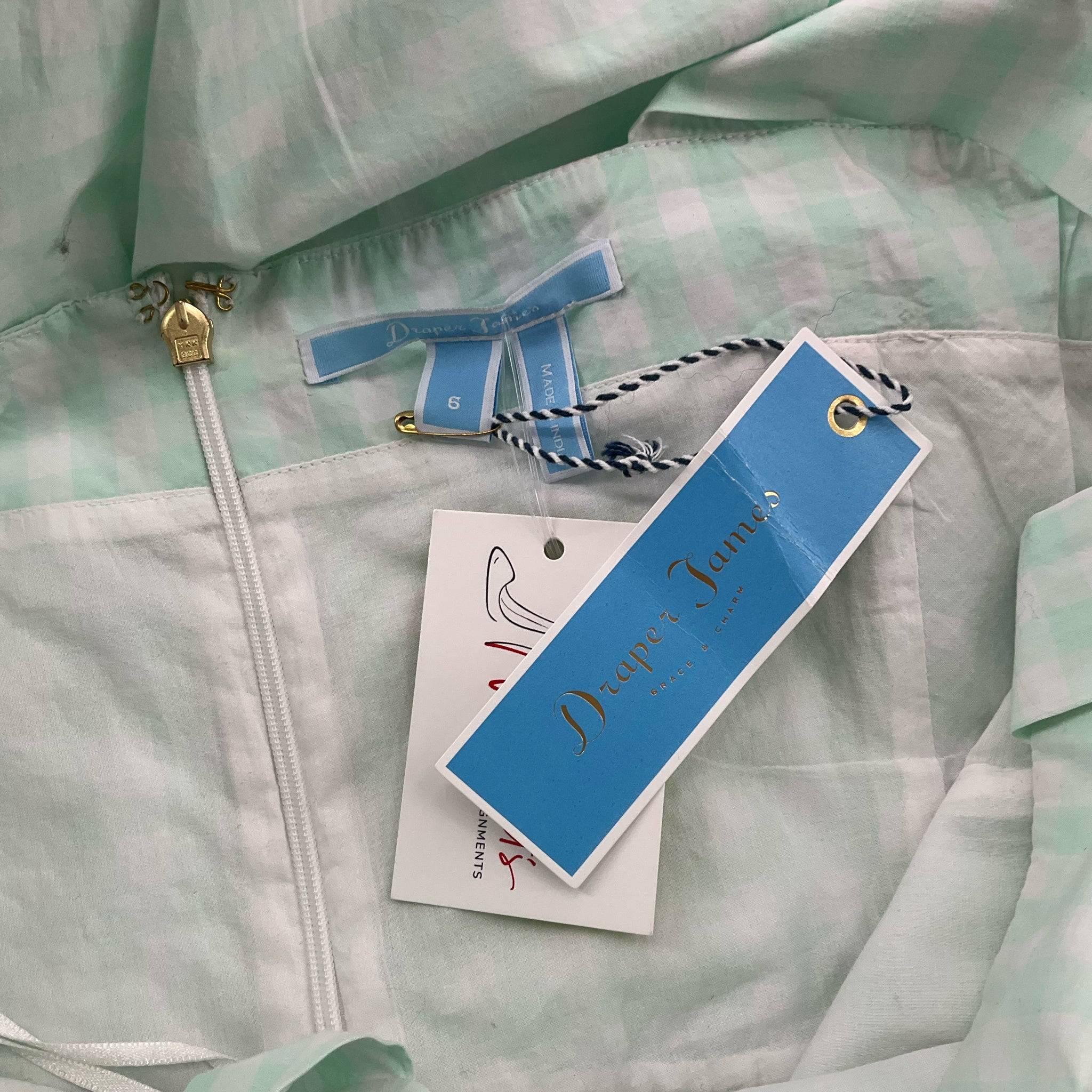 Close-up of Draper James brand tags on white/mint checkered dress, size 6, showcasing authenticity and new condition for resale.