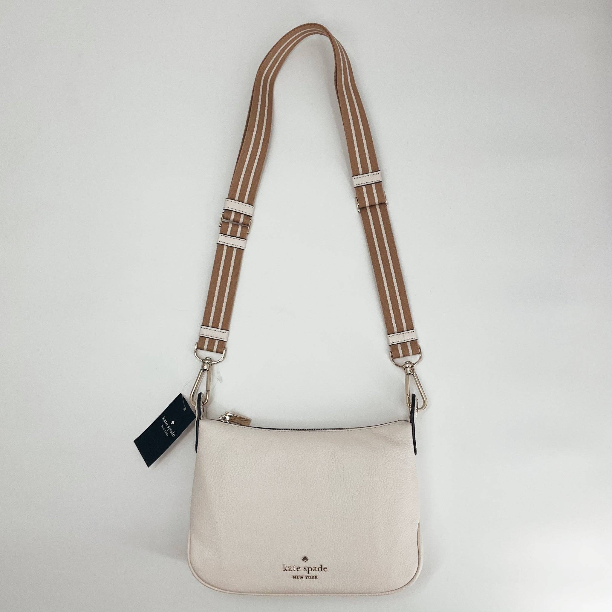 Kate Spade cream pebble crossbody bag with adjustable tan and white striped strap, new with tags at Margaret’s Fine Consignments.