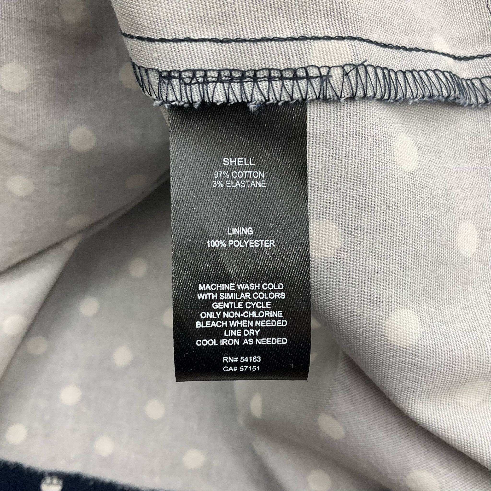 Fabric care tag showing material details of Jessica Howard sleeveless navy and white polka dot mini dress size 12, Margaret’s Fine Consignments.