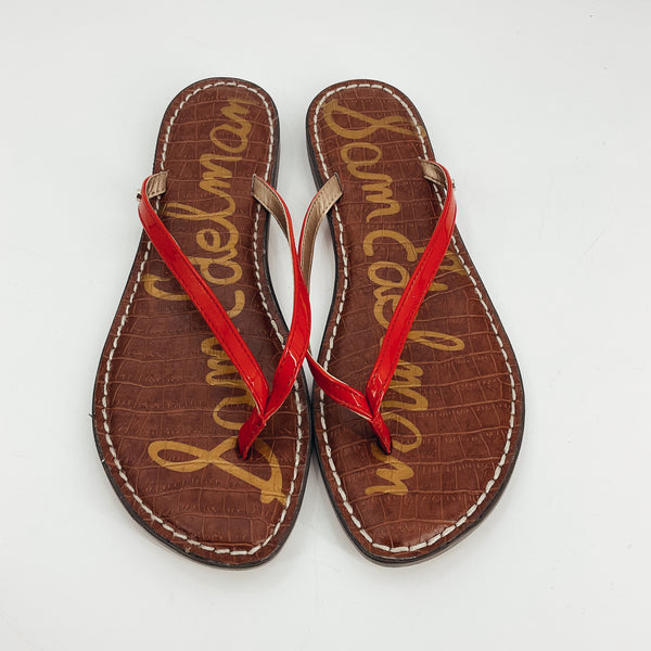 Top view of Sam Edelman Gracie red thong sandals, featuring glossy red straps, gold SE logo, and stitched croc-embossed footbed. Stylish pre-owned beachwear in size 8.5.