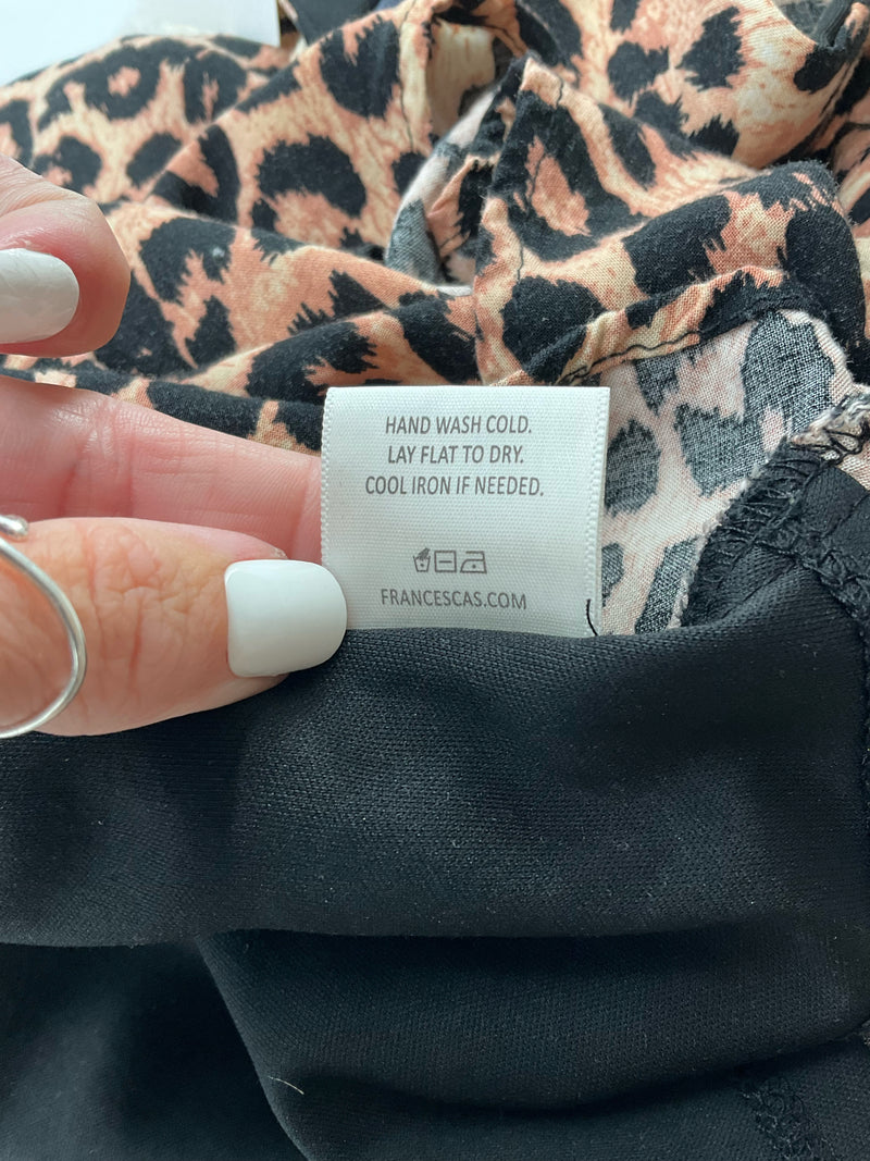 Care label of Blue Rain Brown/Black Print Dress with washing instructions and Francescas.com branding for garment maintenance.