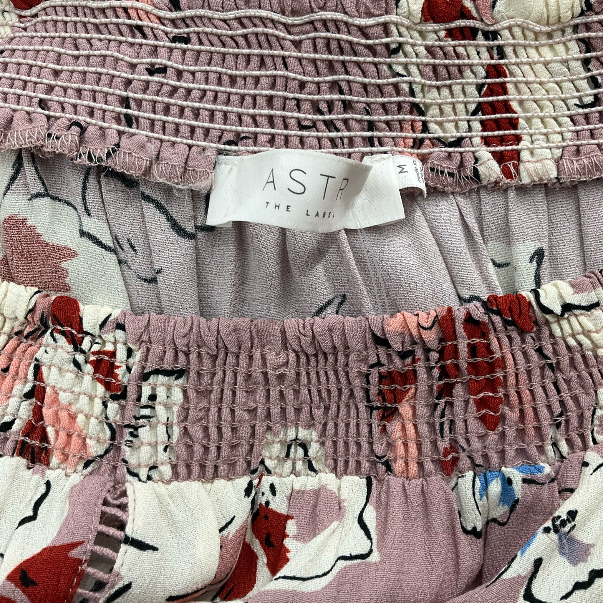 Close-up of Astr brand label on Dusty Lavender/Multi Floral Top - Size Medium, confirming authenticity and gently used quality.