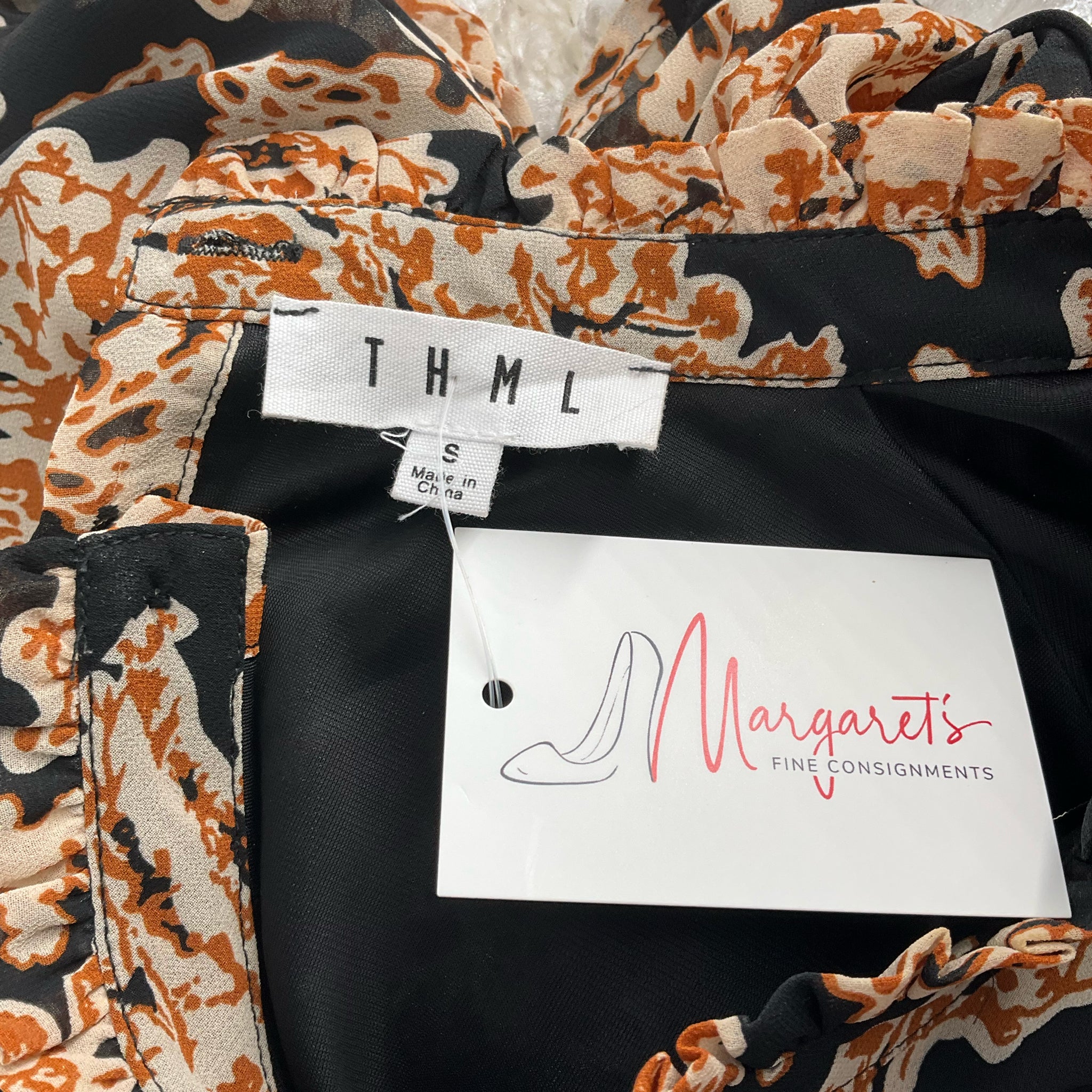 Close-up of THML brand label and Margaret’s Fine Consignments tag on Black/Camel Flora Dress - Size Small, confirming authenticity and resale origin.