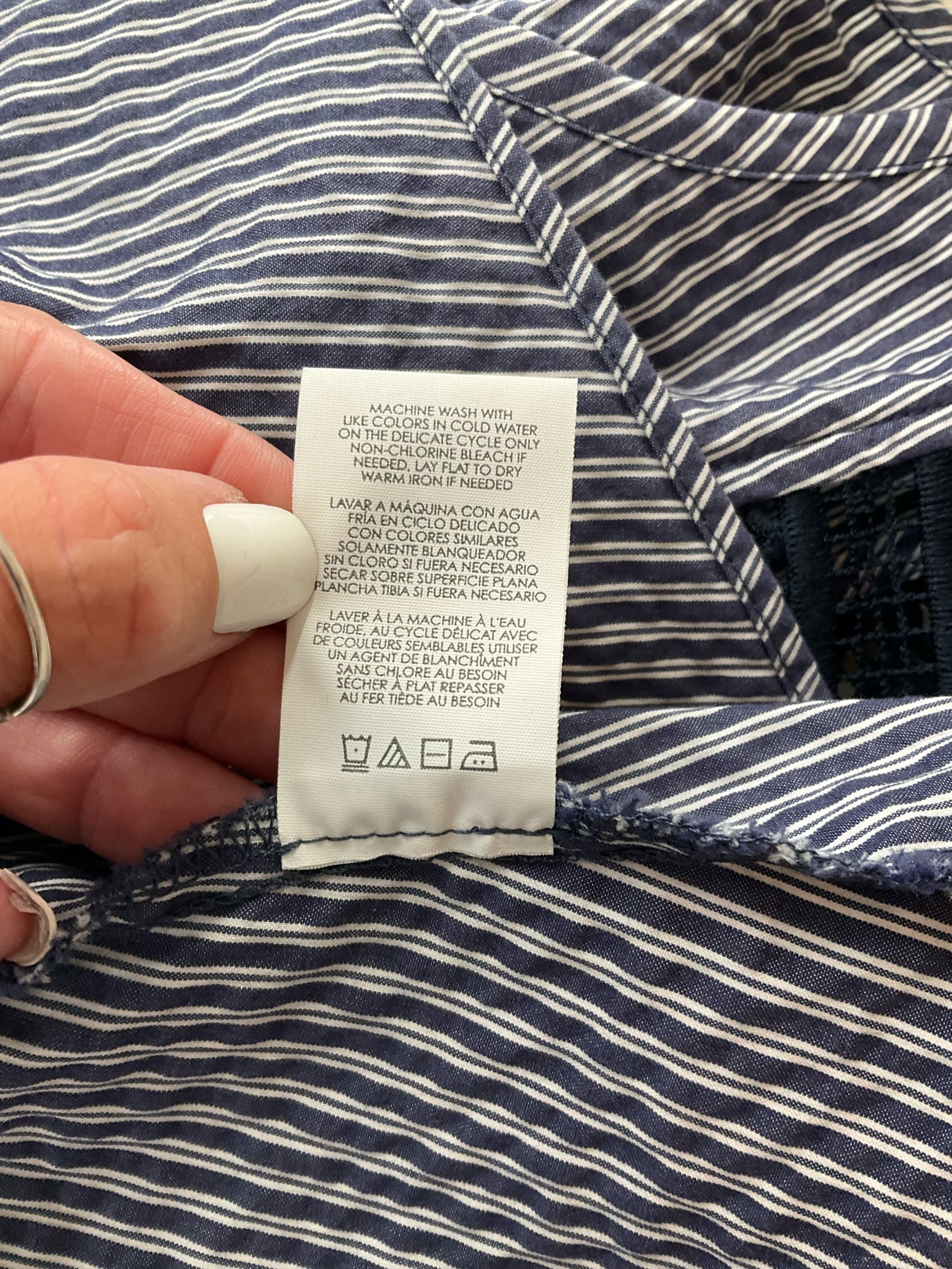 Care instructions tag of Cabi Tapestry Top XS, detailing machine wash guidelines and fabric care symbols for cotton blend material.