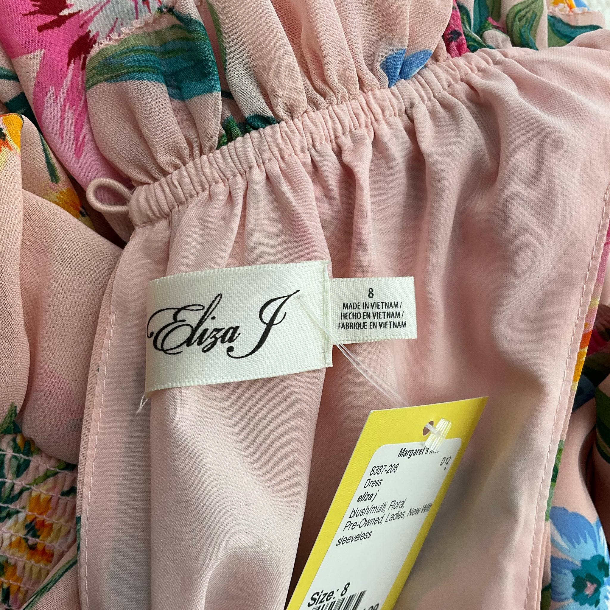 Close-up of Eliza J brand label and size 8 tag on blush floral mini dress, new with tags at Margaret’s Fine Consignments.