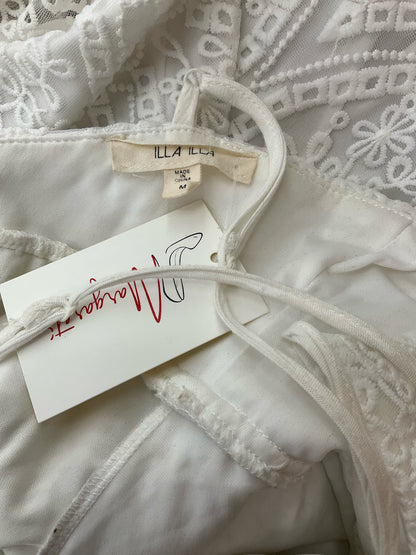 Close-up of Illa Illa dress label showing brand tag and size medium, confirming authenticity of pre-owned white lace skater dress.