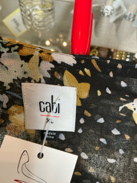 Close-up of Cabi brand label on Black/Blue Ladies Pre-Owned Top - Size XL, highlighting brand authenticity and floral fabric detail.