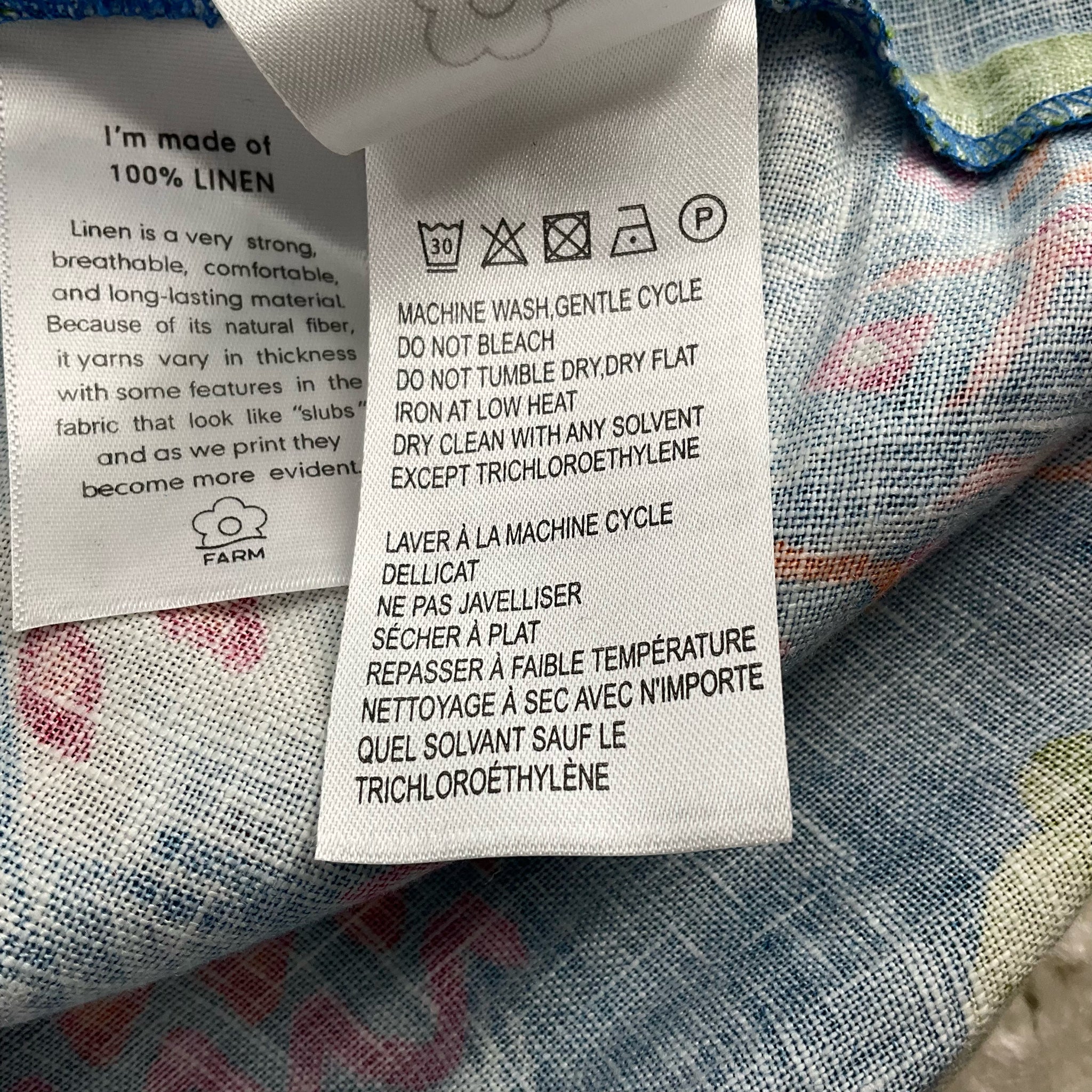 Care label on Farm Blue/Green Tropical Dress - Size Small with washing instructions and fabric details, ensuring proper garment maintenance.