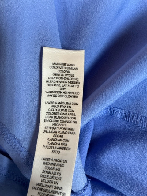 Care label of Chico’s blue solid top, size XL, detailing machine wash instructions and fabric care for maintaining quality and longevity.