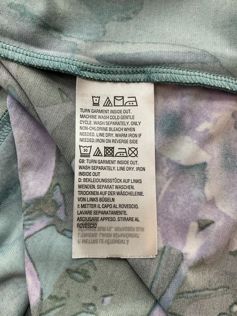 Care label on Bob Mackie Green/Purple Floral Pre-Owned Ladies Top - Size XS, detailing washing instructions and fabric care symbols.