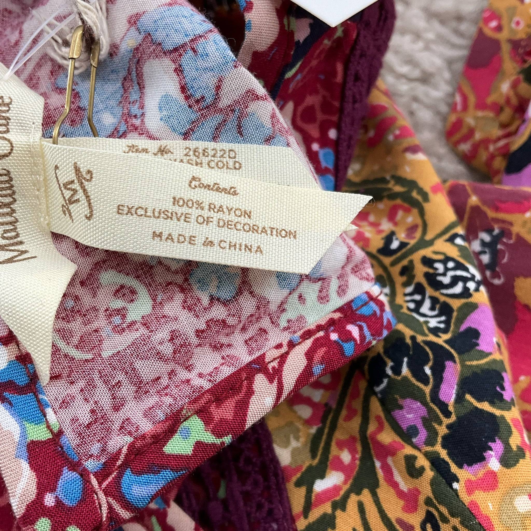 Fabric content tag showing 100% rayon material on Matilda Jane maroon floral dress, size medium. Available at Margaret’s Fine Consignments.