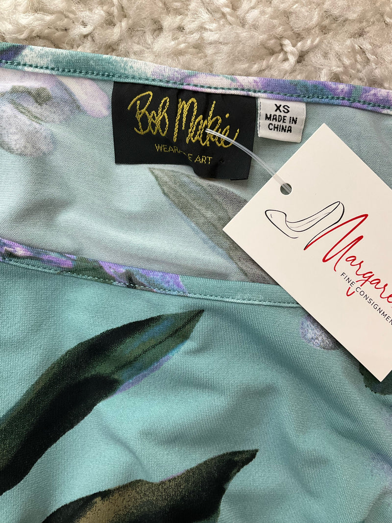 Close-up of Bob Mackie Wearable Art label on Green/Purple Floral Pre-Owned Ladies Top - Size XS, confirming designer authenticity.