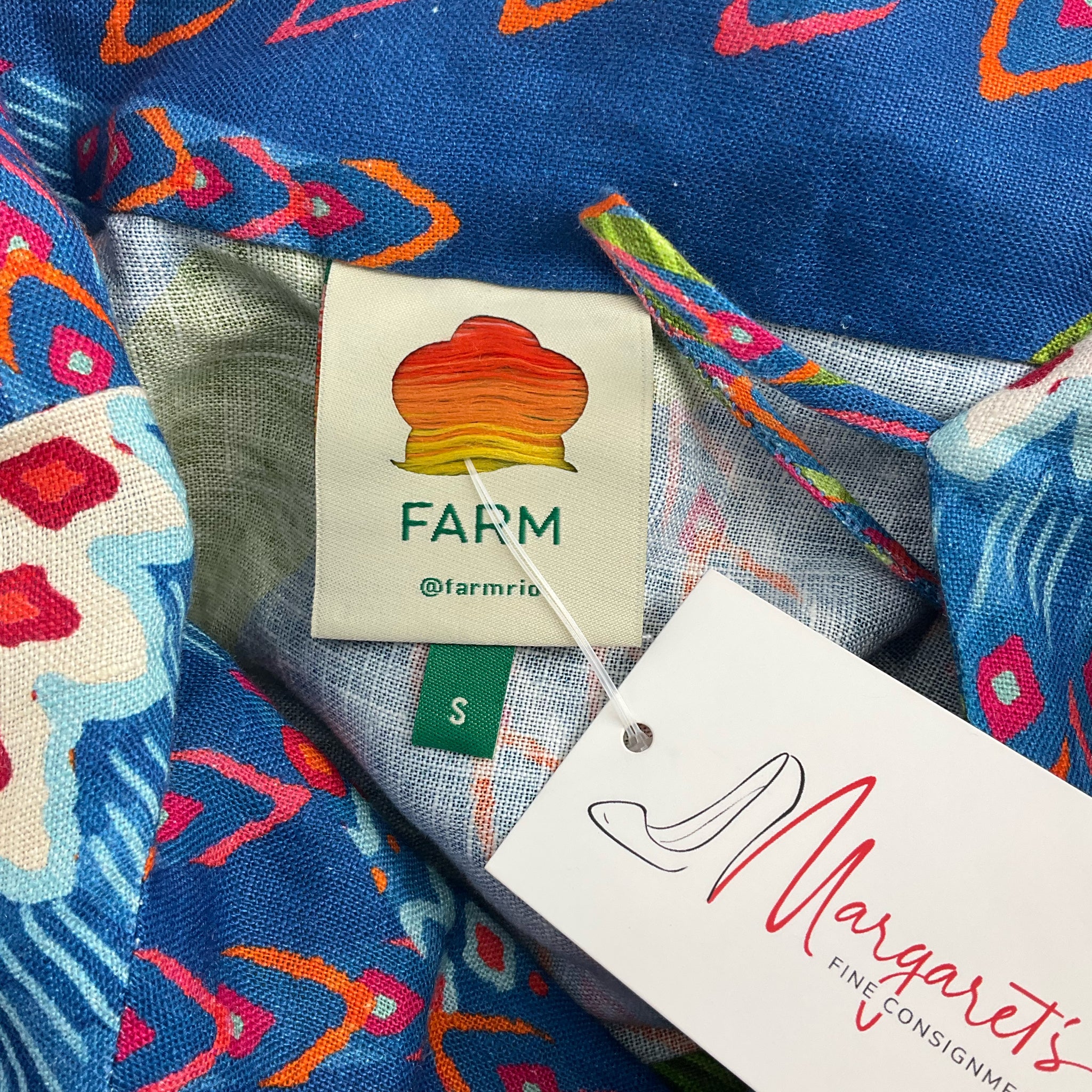 Close-up of Farm brand label and Margaret's Fine Consignments tag on Blue/Green Tropical Dress - Size Small, confirming authenticity and size.