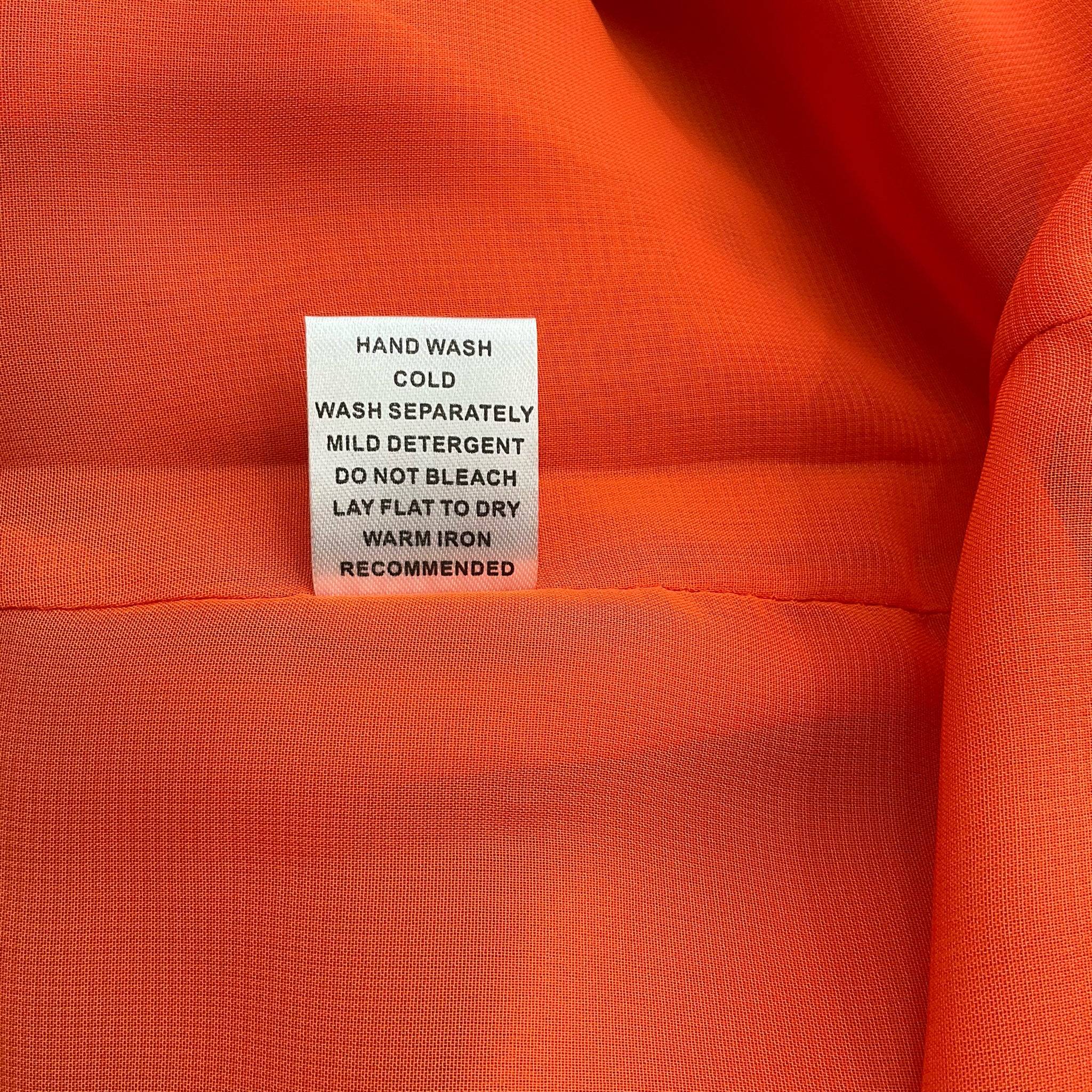 Care instructions tag for Jade orange mini dress, recommending hand wash cold, lay flat to dry, and warm iron if needed.