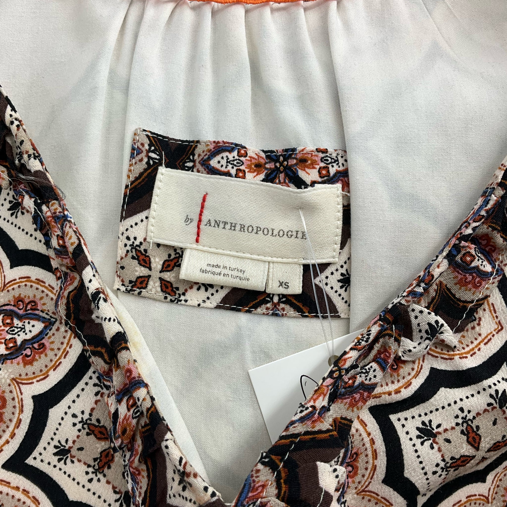 Close-up of Anthropologie brand label on Brown/Orange Print Dress - Size XS, confirming authenticity and size.