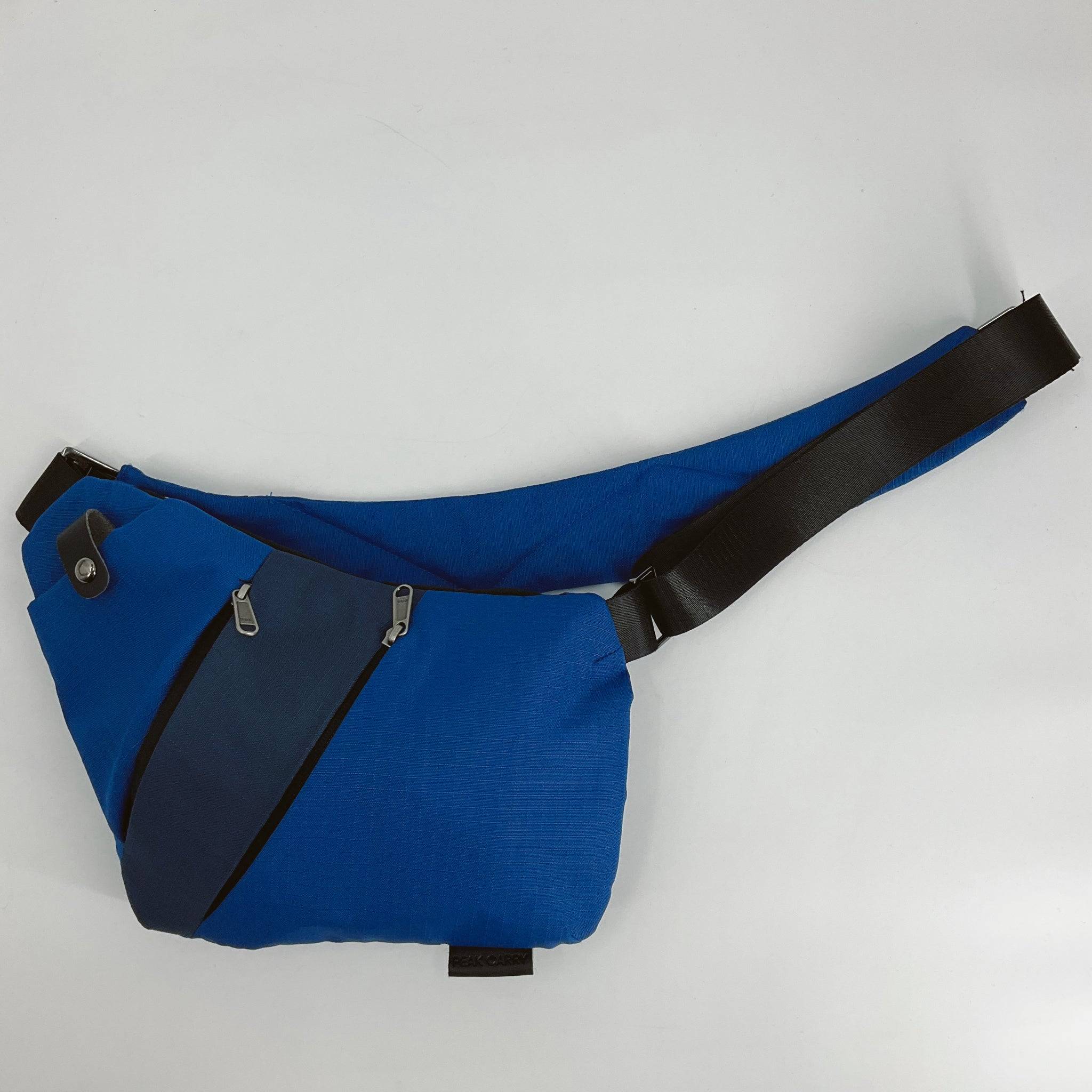 Peak Carry Blue/black Crossbody Bag with adjustable strap and dual zippered compartments, ideal for travel or daily use.