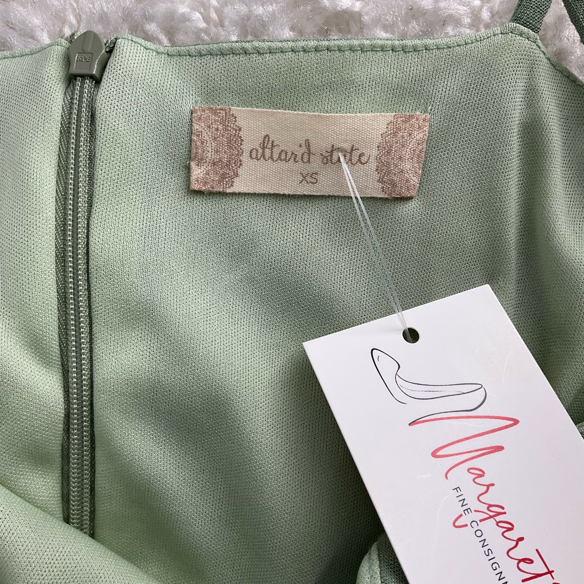 Close-up of Altar'd State brand label and Margaret’s Fine Consignments tag on Green Solid Dress - Size XS, gently used condition.