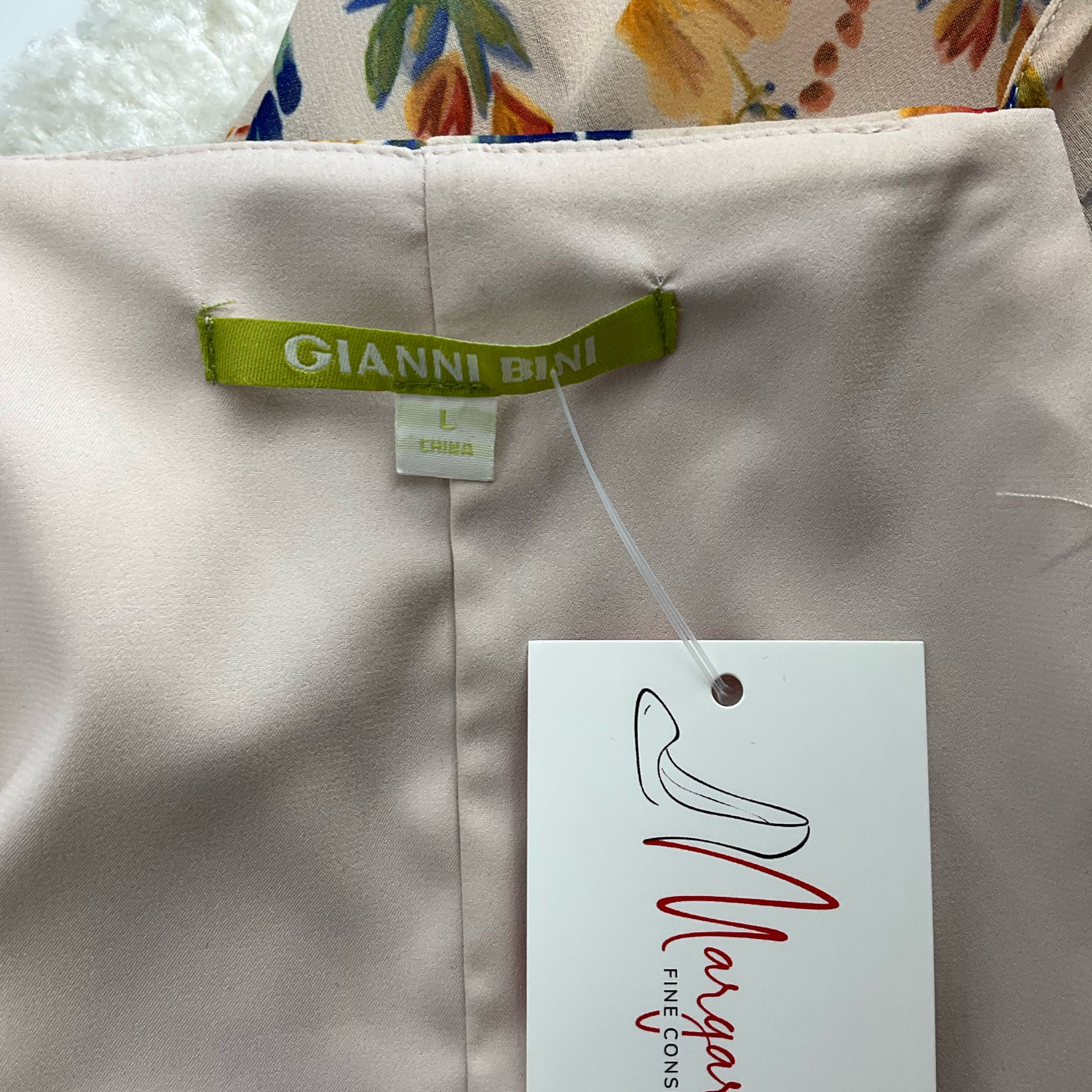 Close-up of Gianni Bini label on Yellow/Blue Floral Dress - Size Large | Features brand tag and Margaret’s Fine Consignments label.
