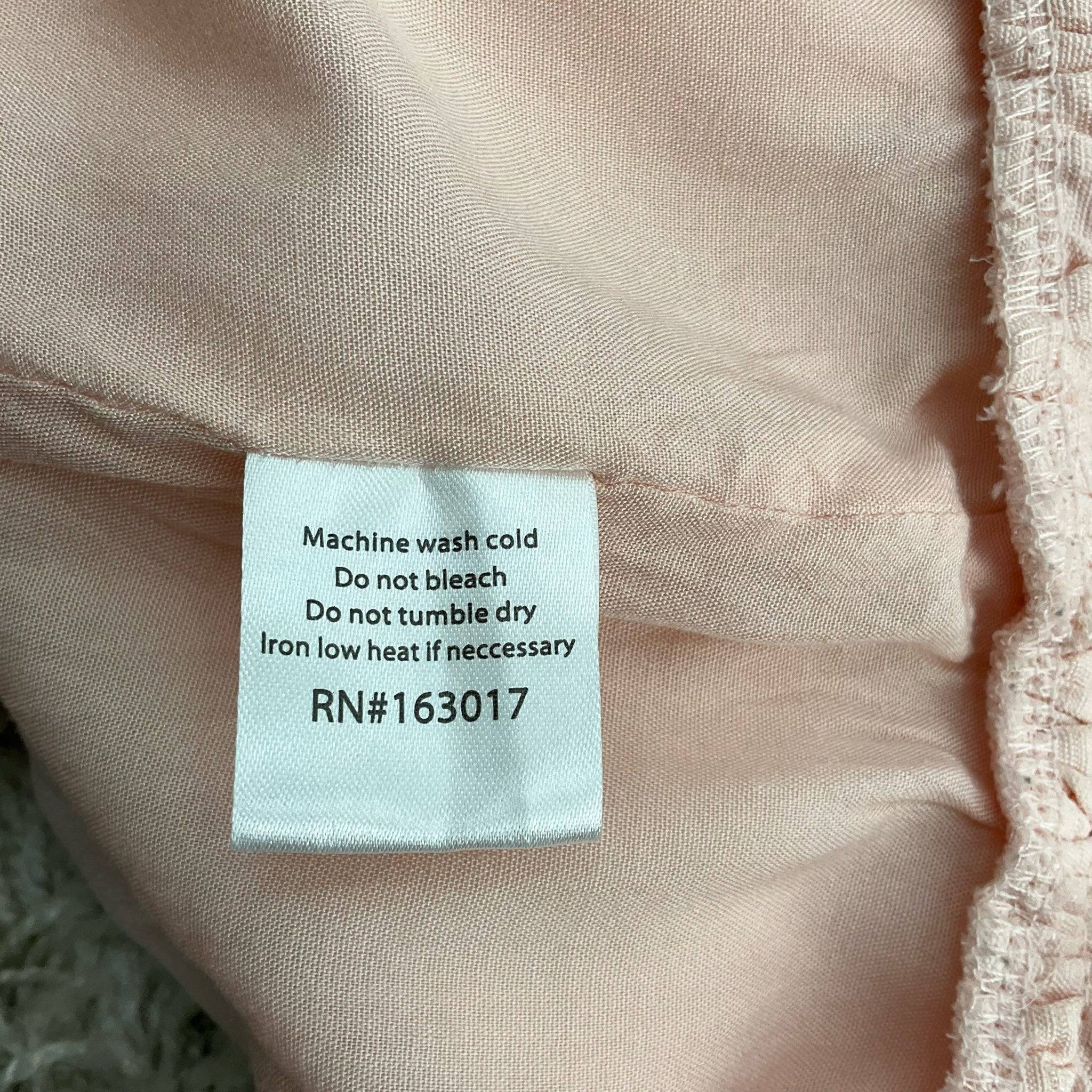 Care instructions tag for Princess Polly blush fringe mini dress size 12, sold by Margaret’s Fine Consignments.