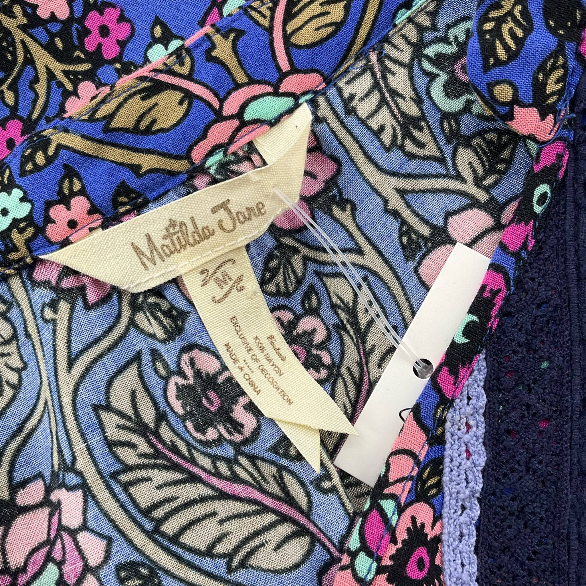 Close-up of Matilda Jane brand tag on blue/multi floral mini dress Size Medium, available at Margaret’s Fine Consignments.
