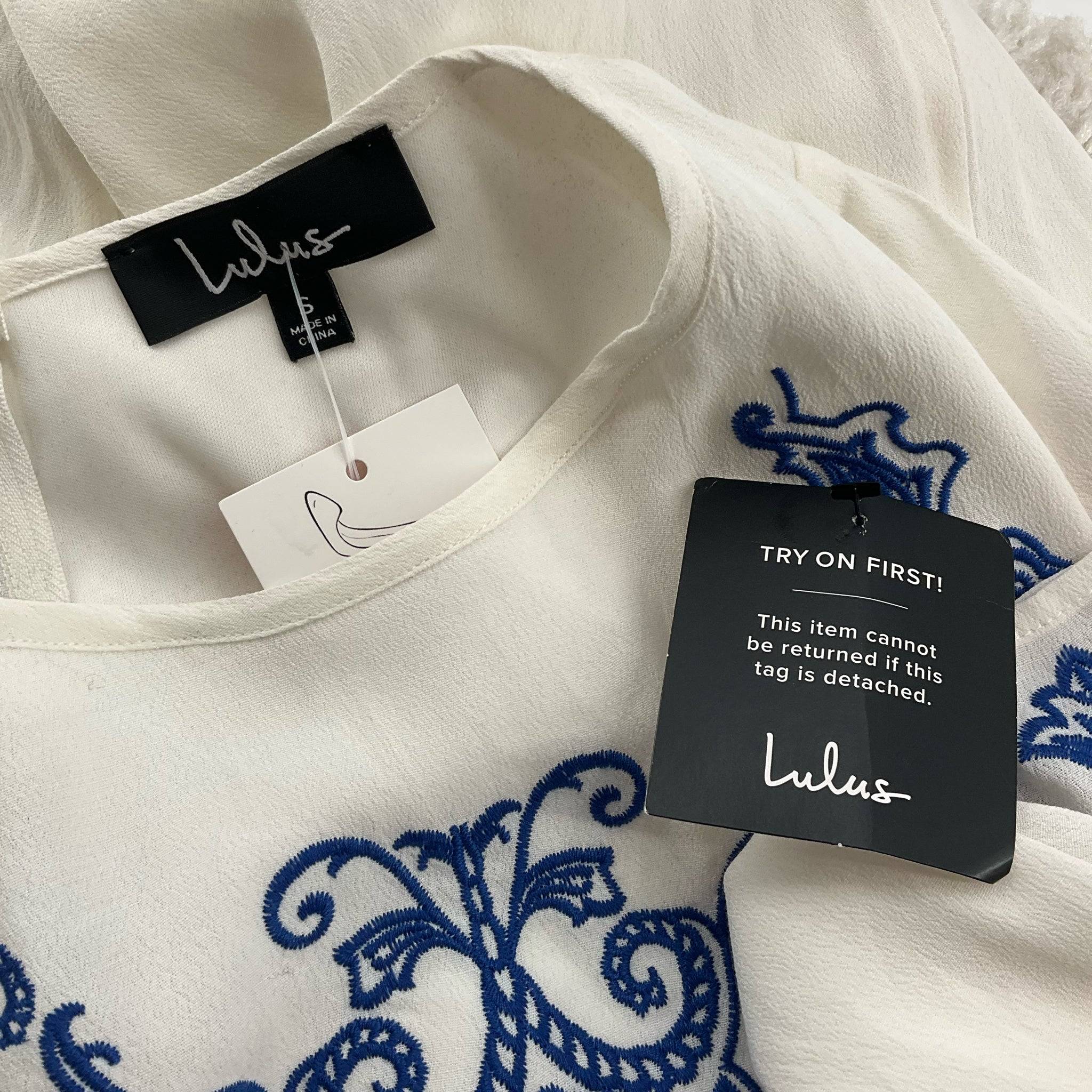 Close-up of Lulus dress tags showing brand and return policy, highlighting new with tags status for Margaret’s Fine Consignments.