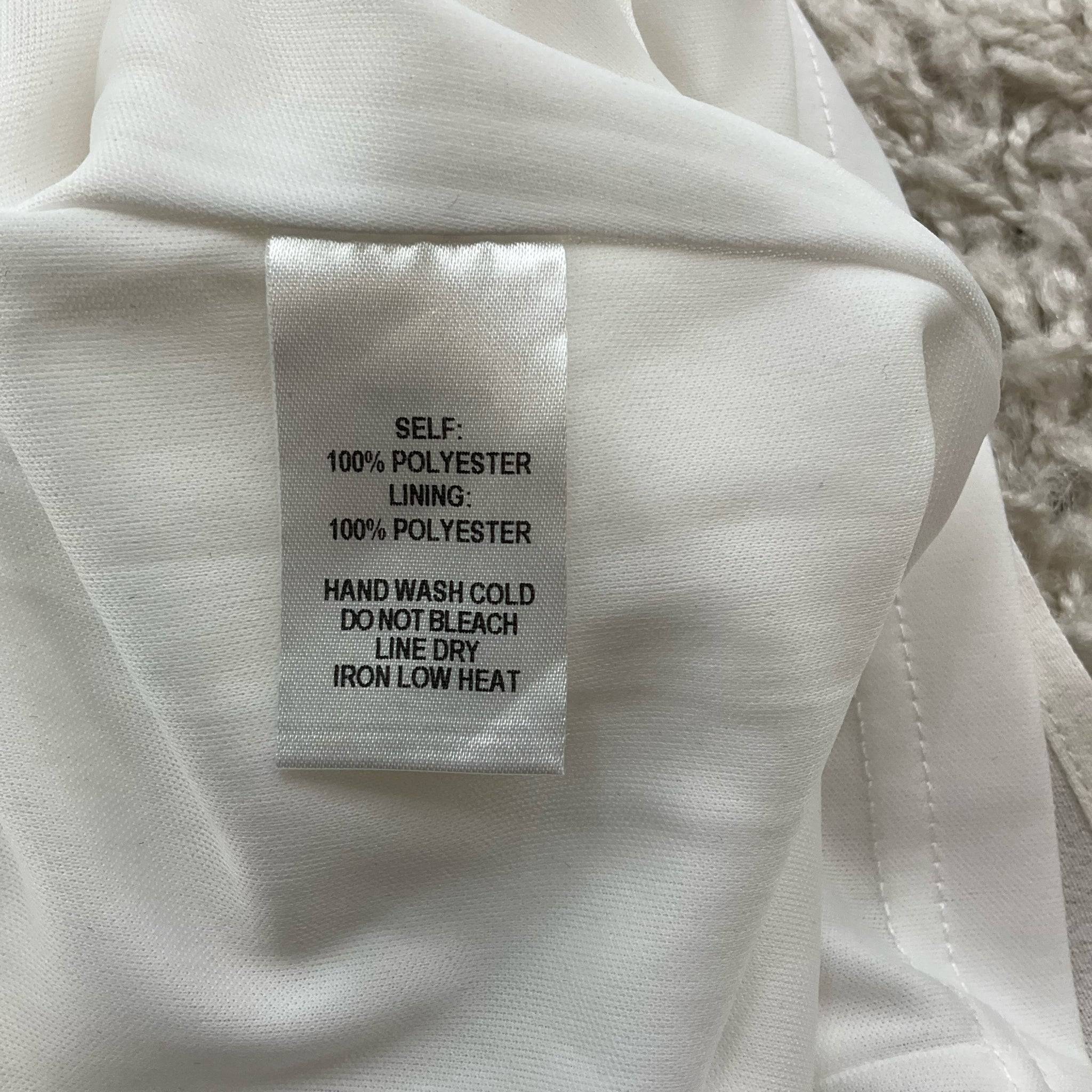 Fabric care label of Lulus white and blue embroidered mini dress, detailing 100% polyester material, listed at Margaret’s Fine Consignments.