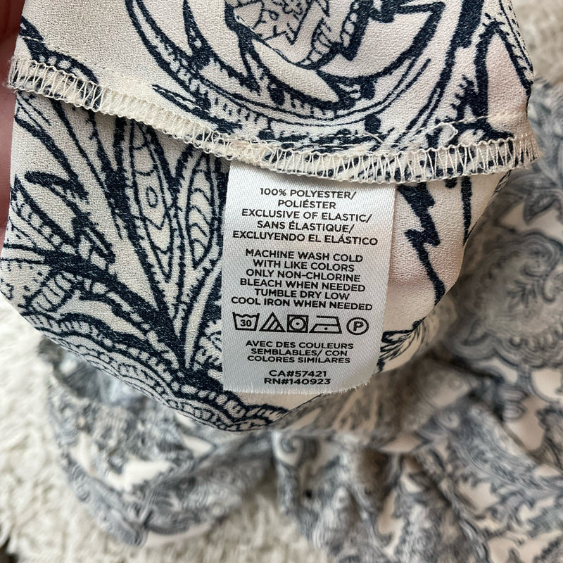 Fabric care label of Loft Paisley Cream/Navy Top XL, showing 100% polyester material and washing instructions for this casual blouse.